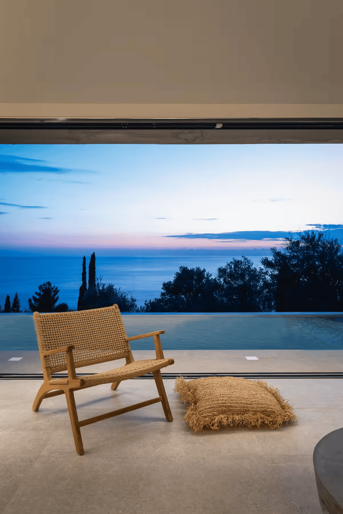 a chair and a rug on a patio by a body of water