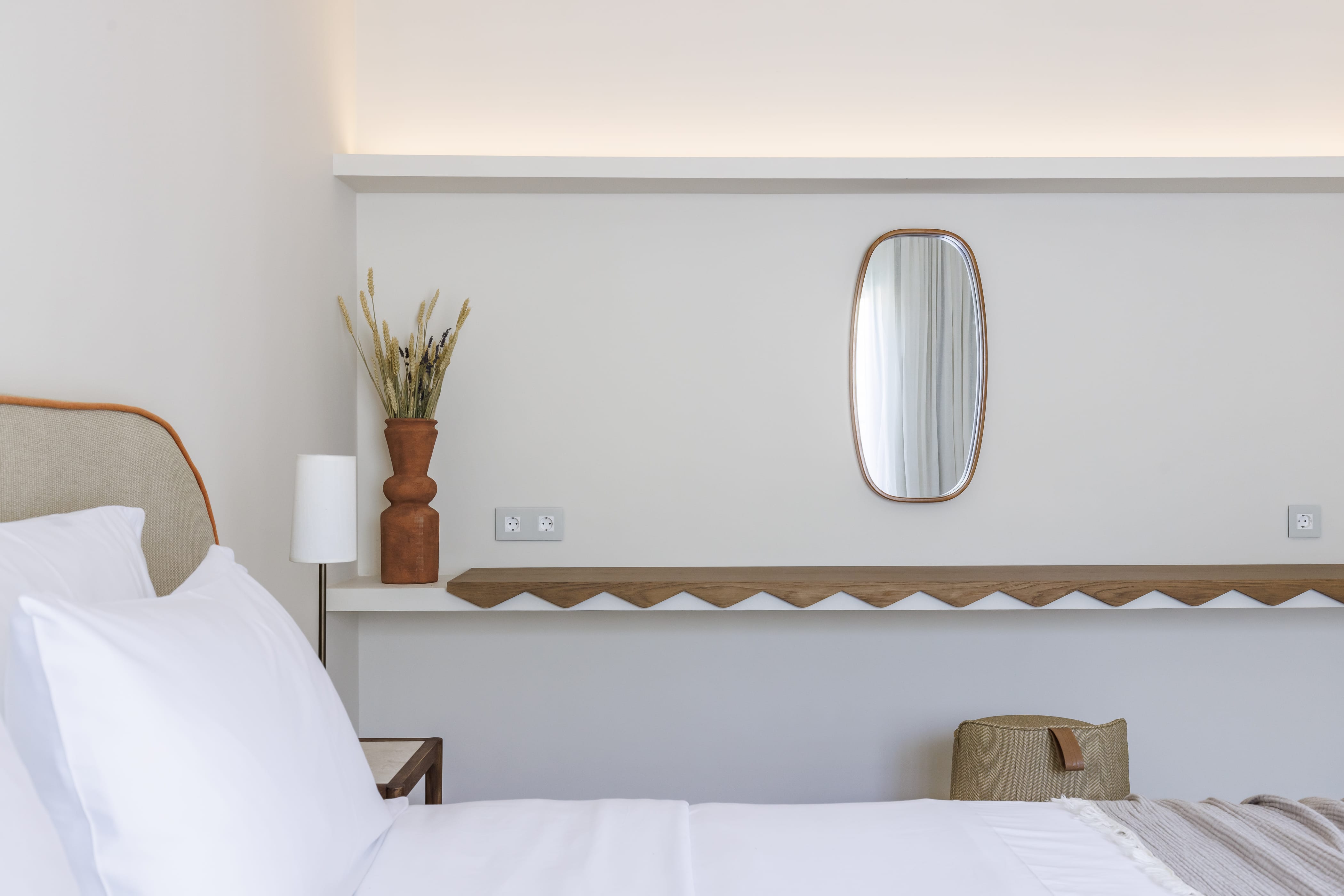 a bed with a mirror and a vase on it