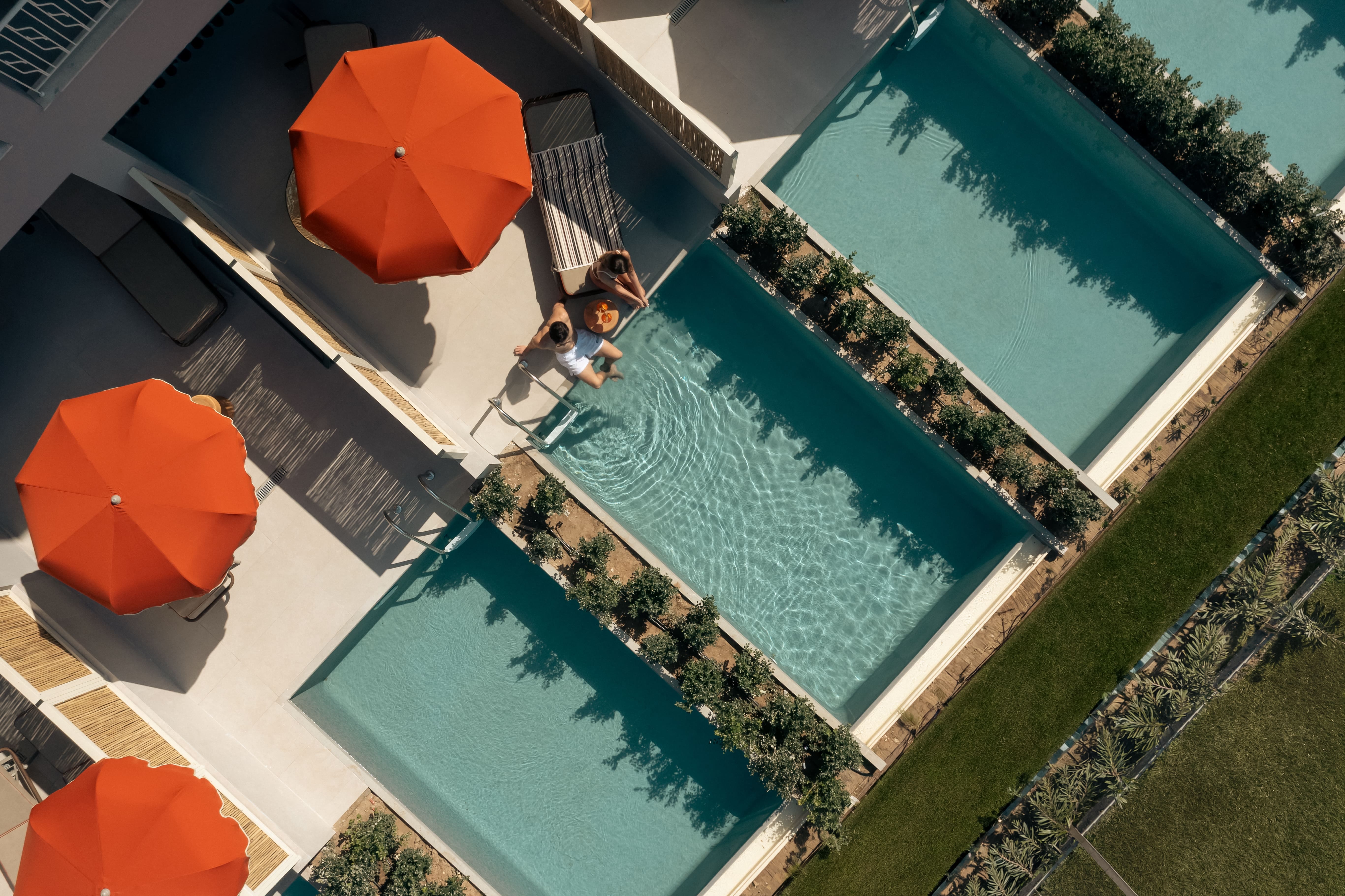 a pool with orange umbrellas and grass