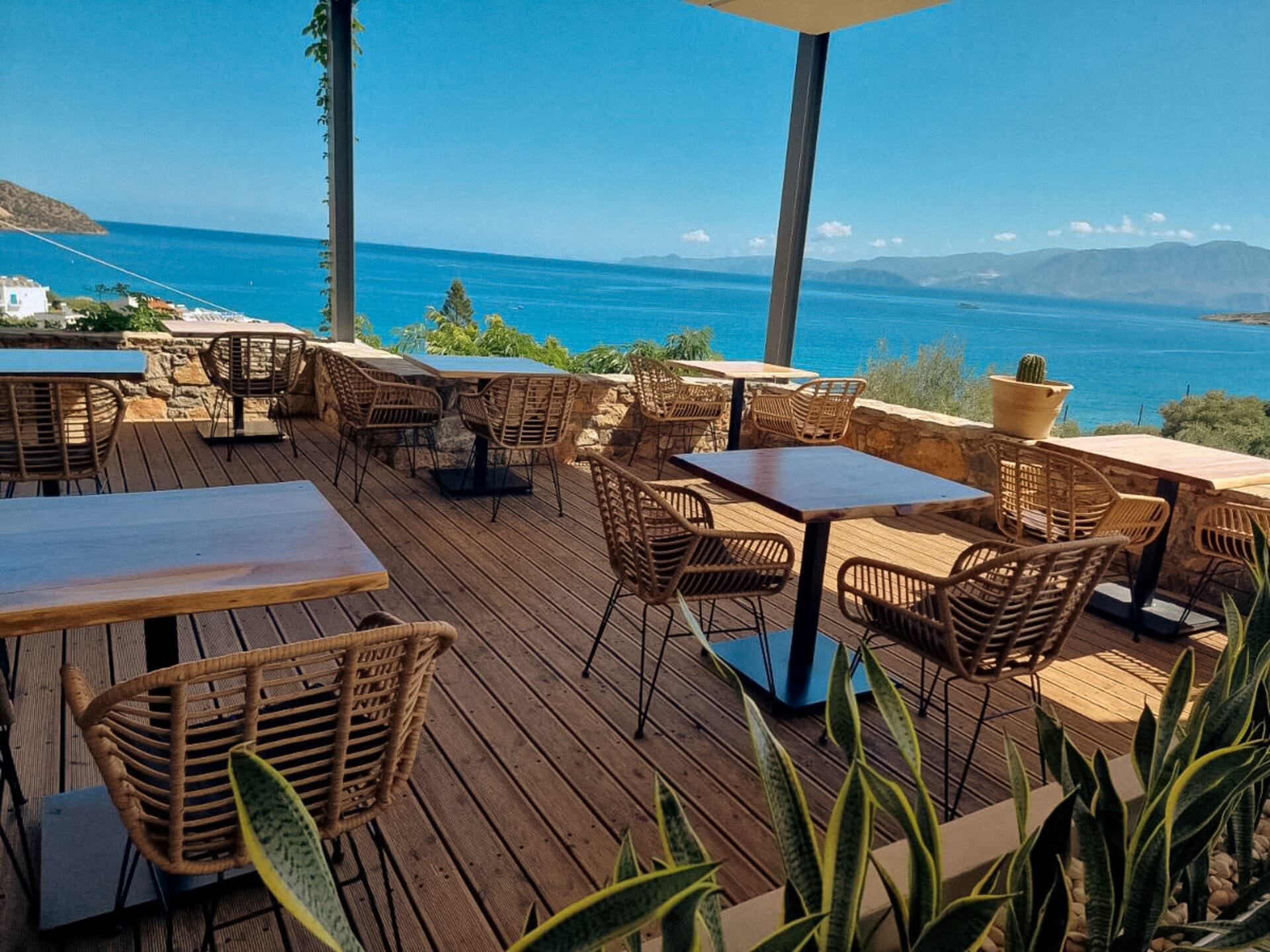 a deck with tables and chairs overlooking the ocean