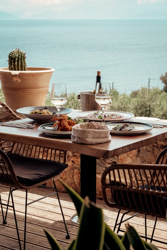a table with plates and glasses on it by a body of water