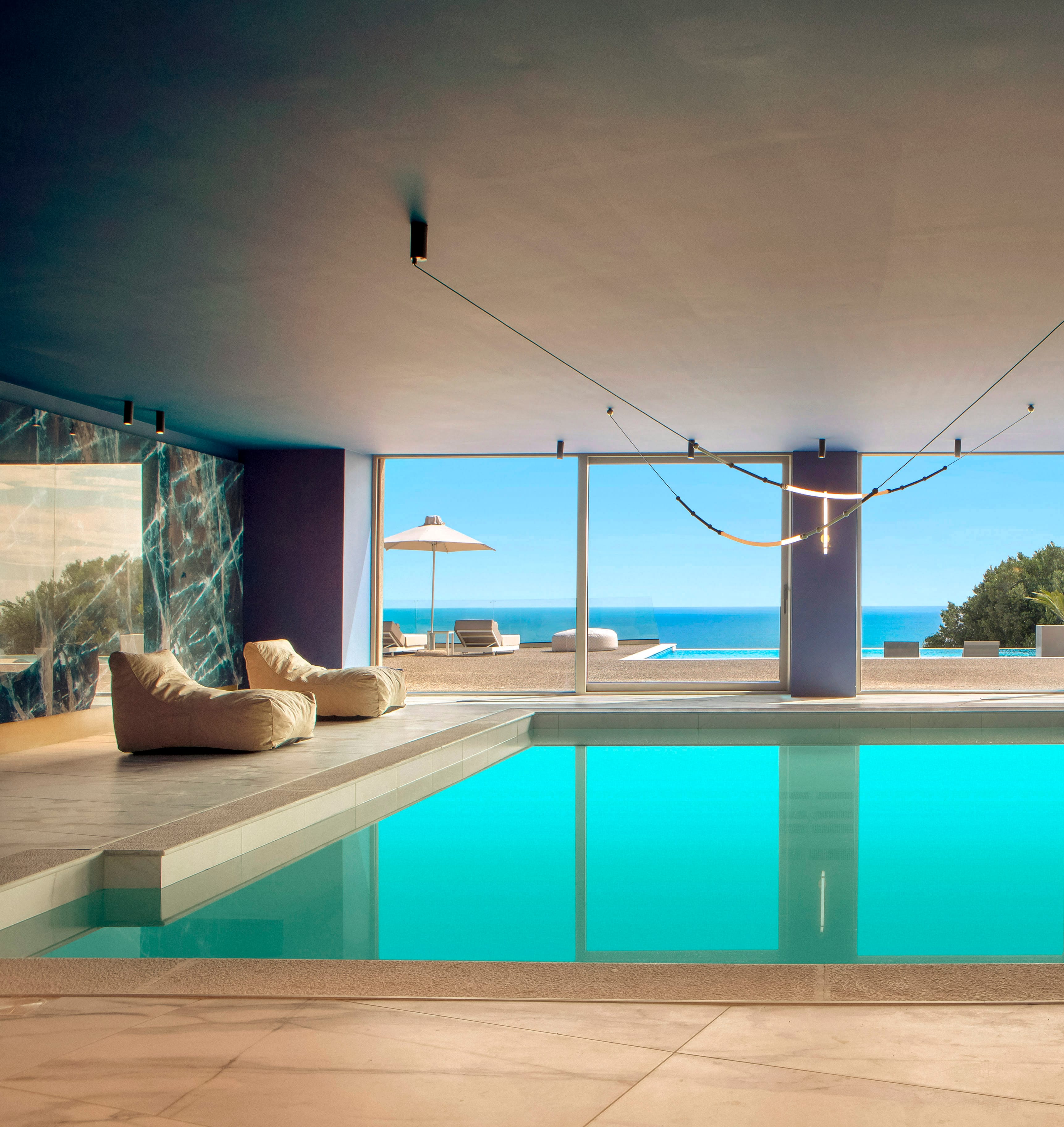 a pool with a view of the ocean and a lounge chair