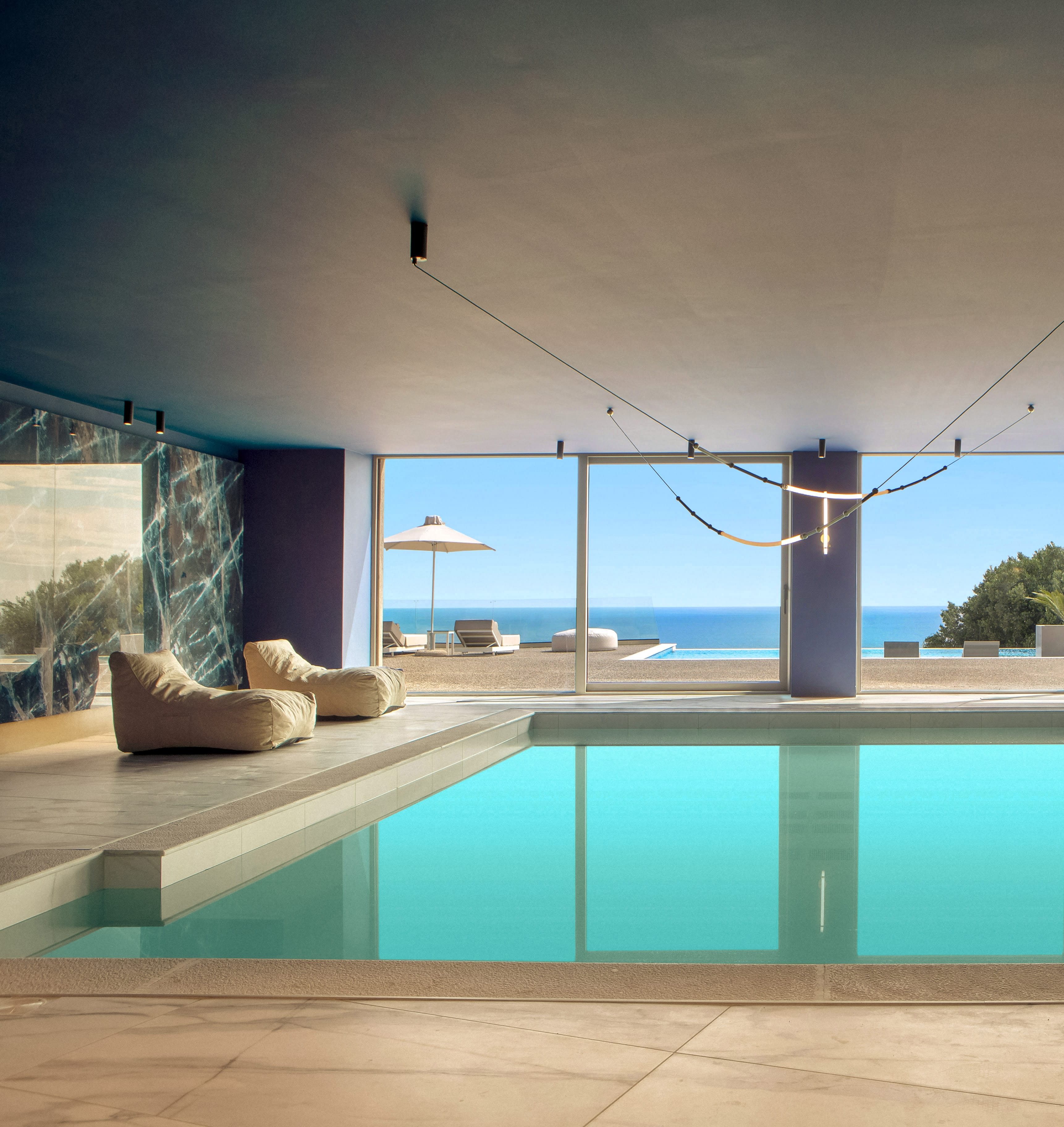 a pool with a view of the ocean and a lounge chair