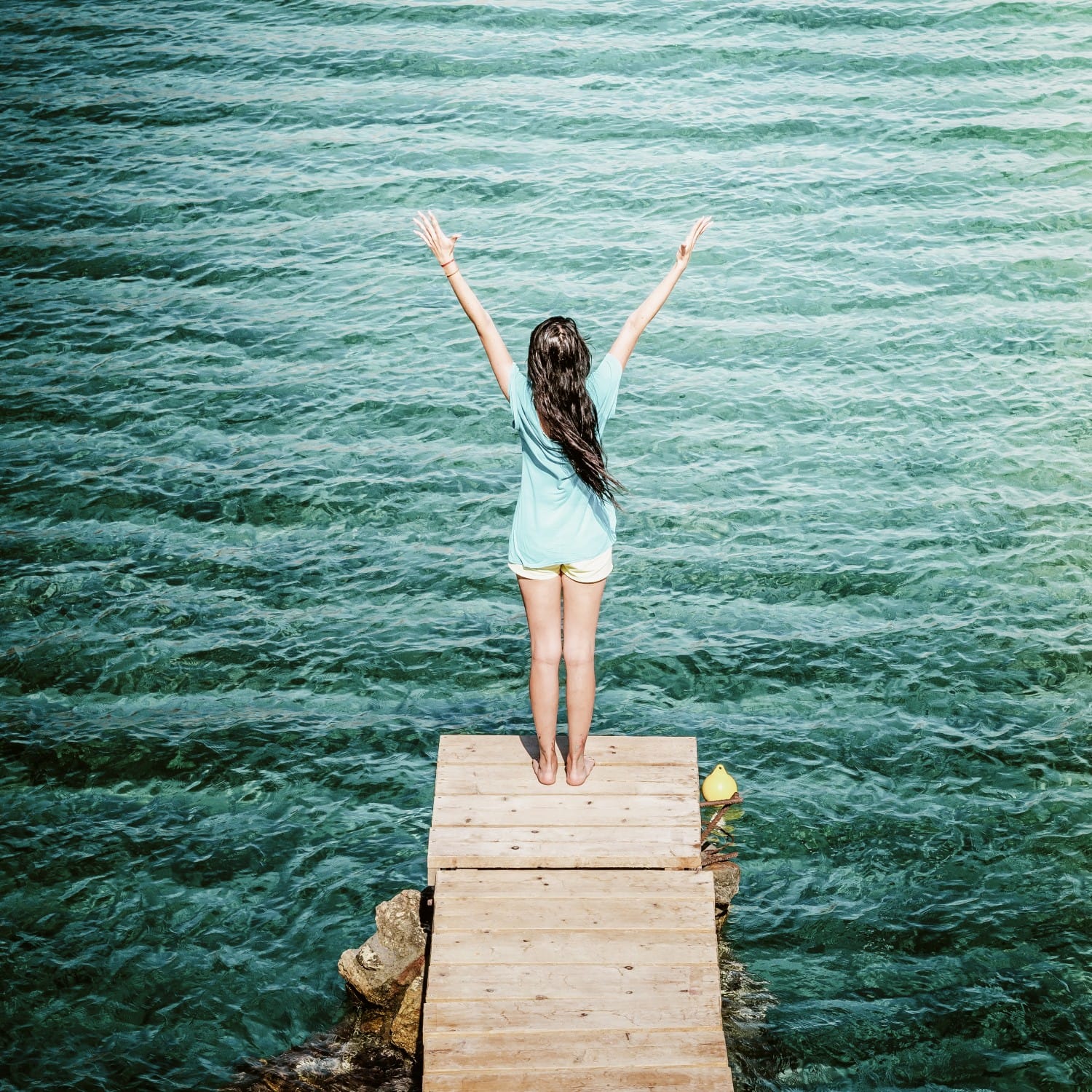 a person standing on a dock over water with the arms up
