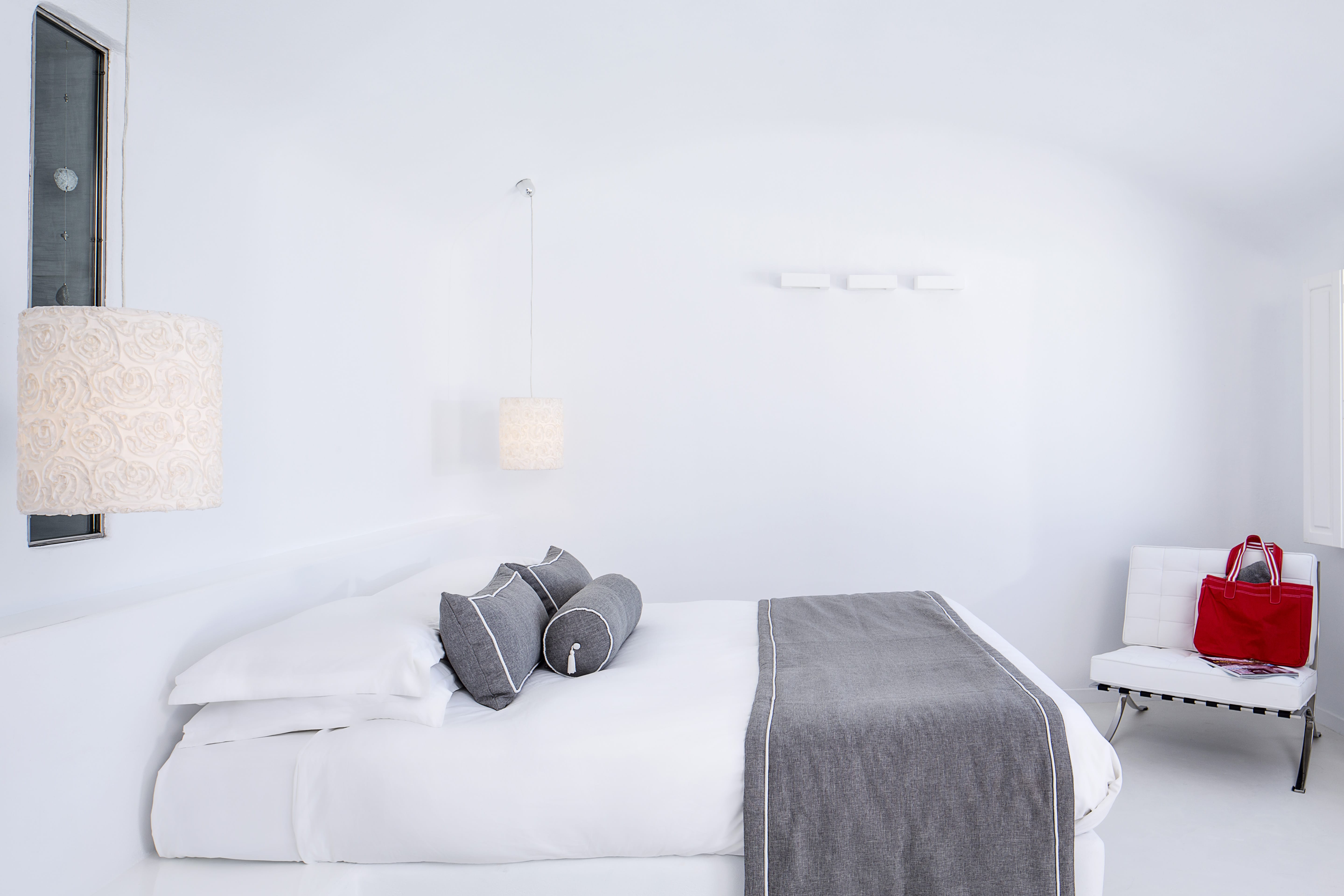 a white bed with a red pillow