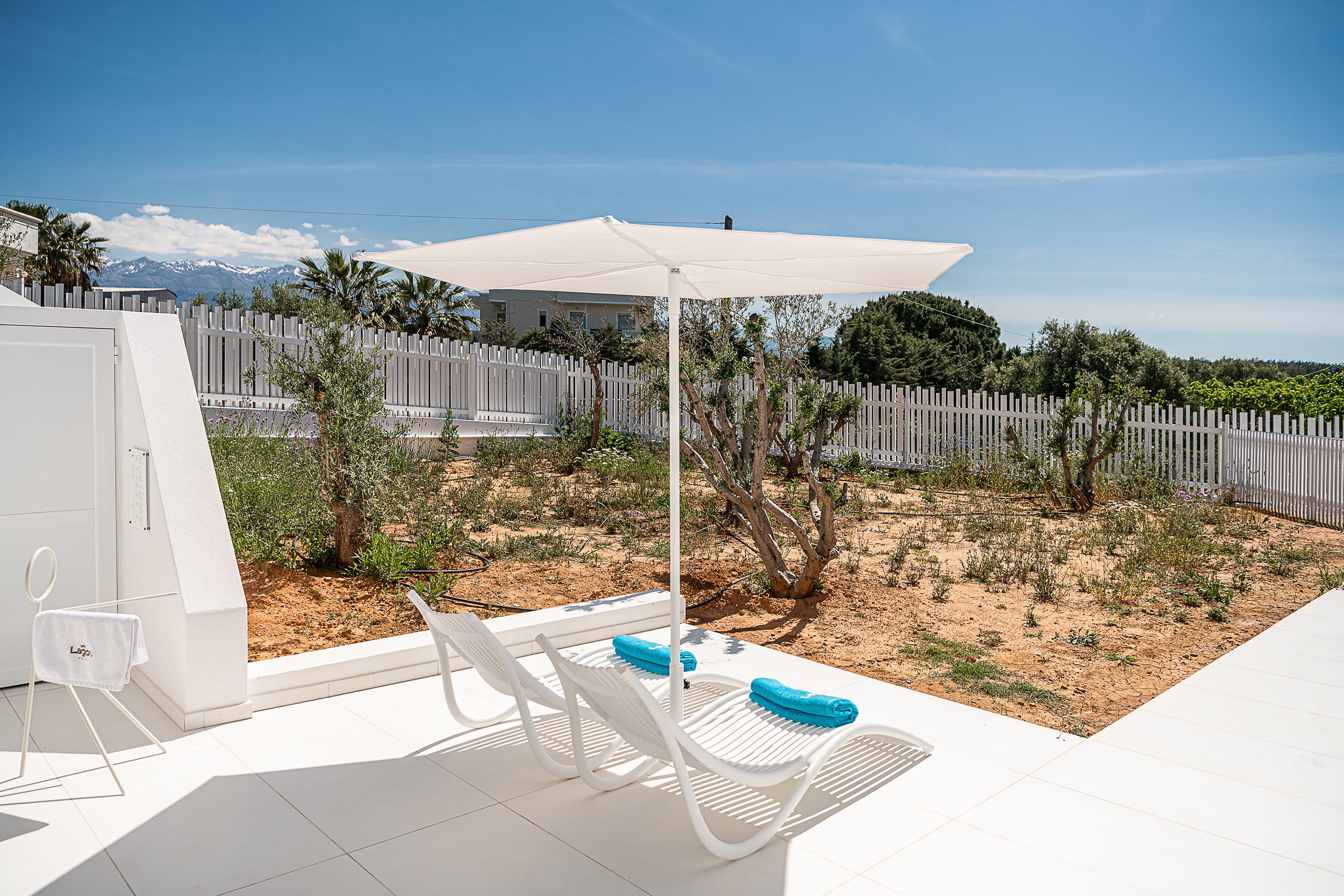 a white deck with a white umbrella and chairs