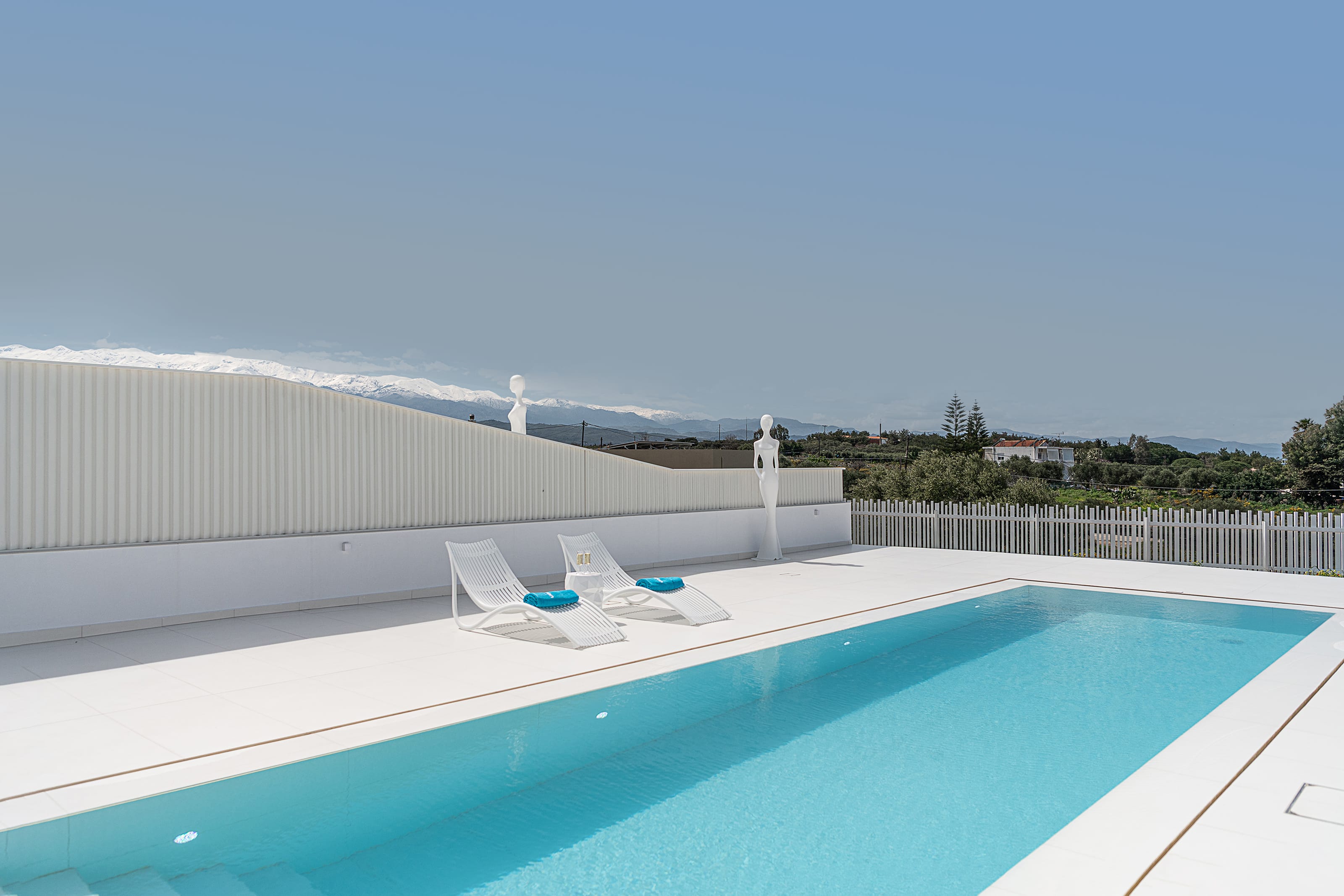 a swimming pool with chairs and a white wall