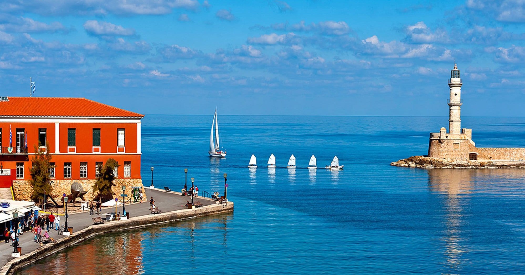 a body of water with a lighthouse and sailboats in it