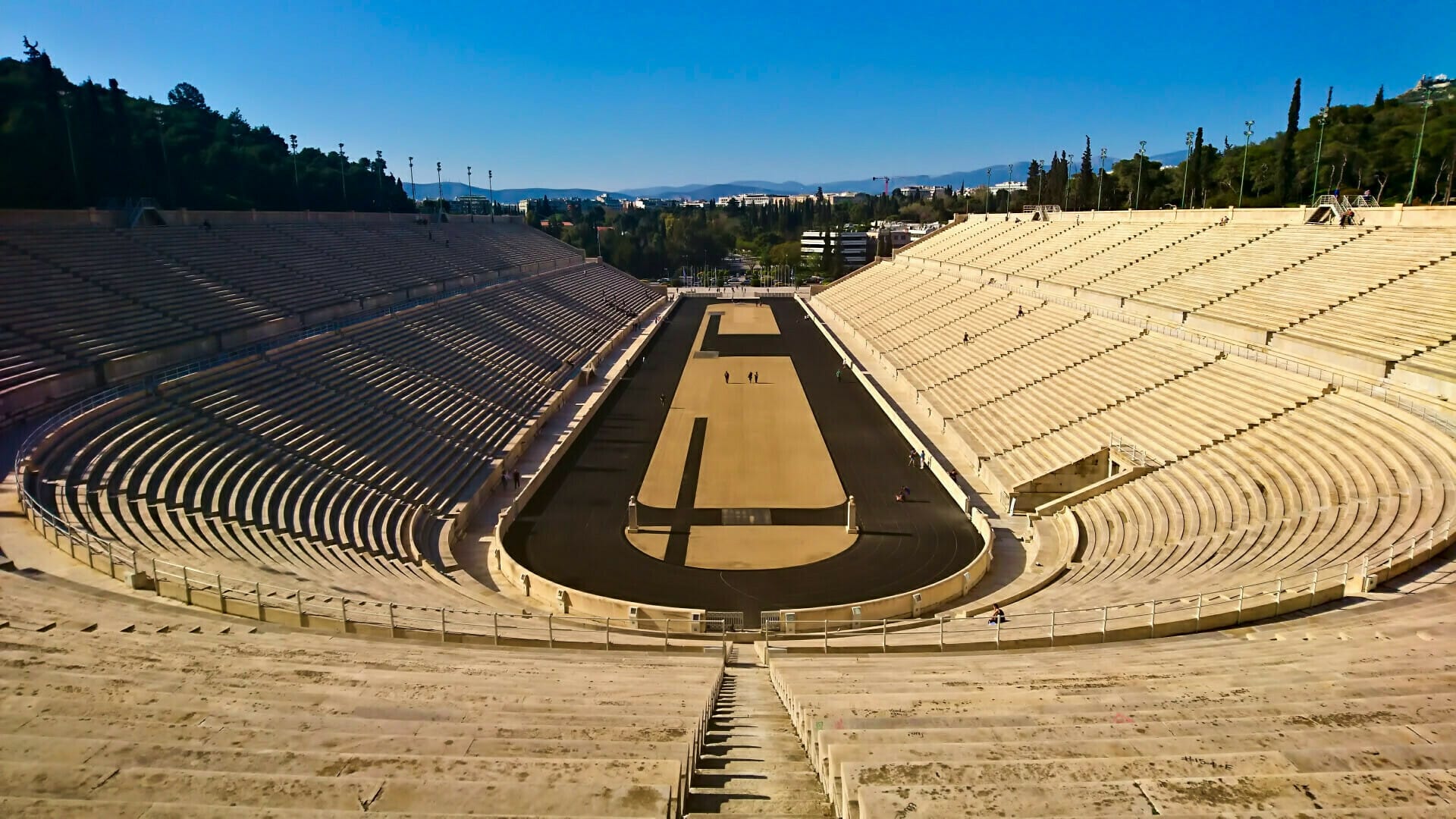 a large pyramid with a few people with Panathenaic Stadium in the background