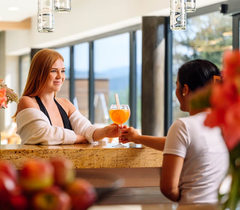 a woman and a man sitting at a table with a drink