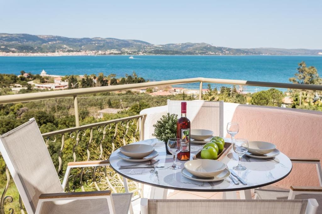 a table with a bottle of wine and glasses on it overlooking a body of water