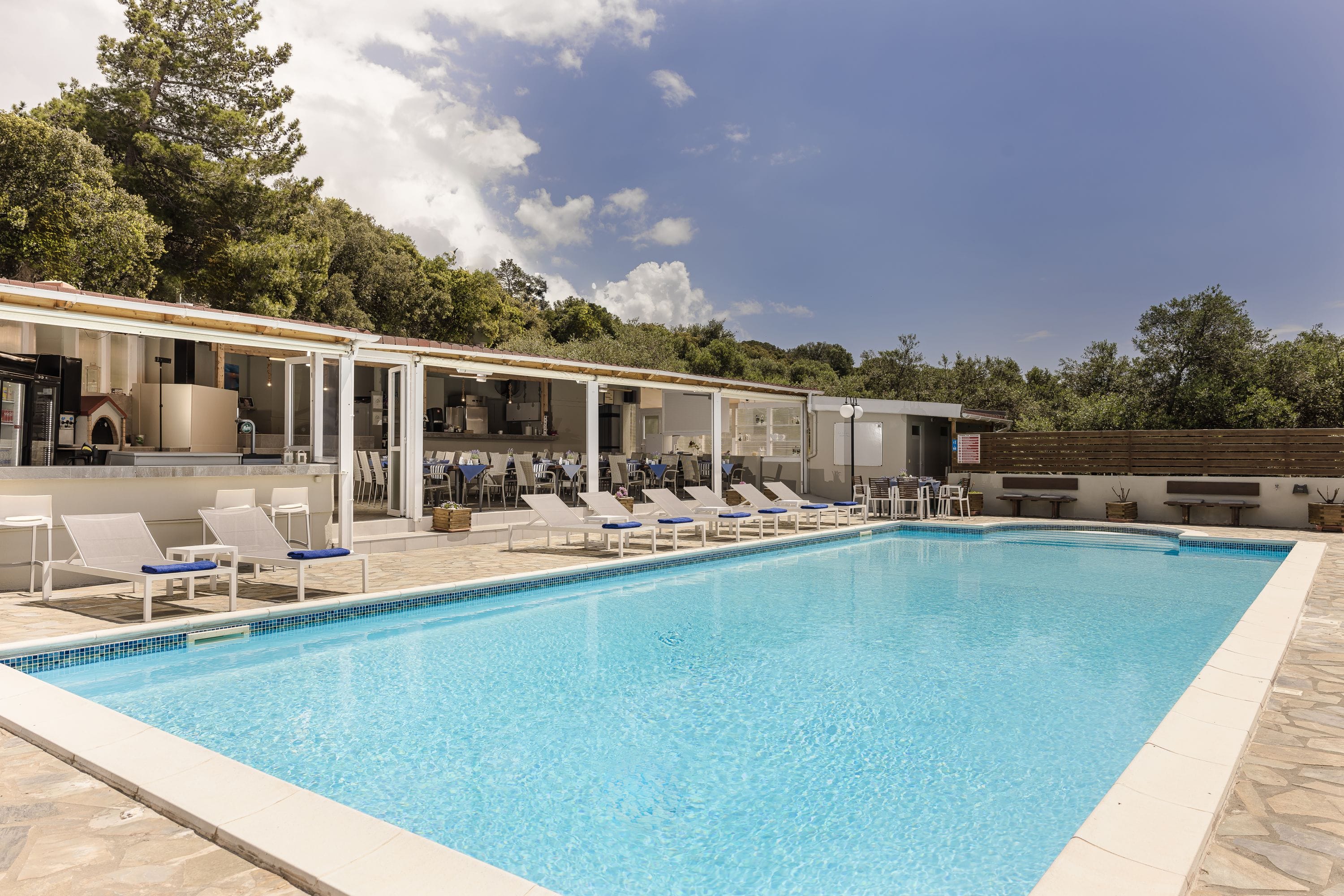 a swimming pool with chairs and a building in the background
