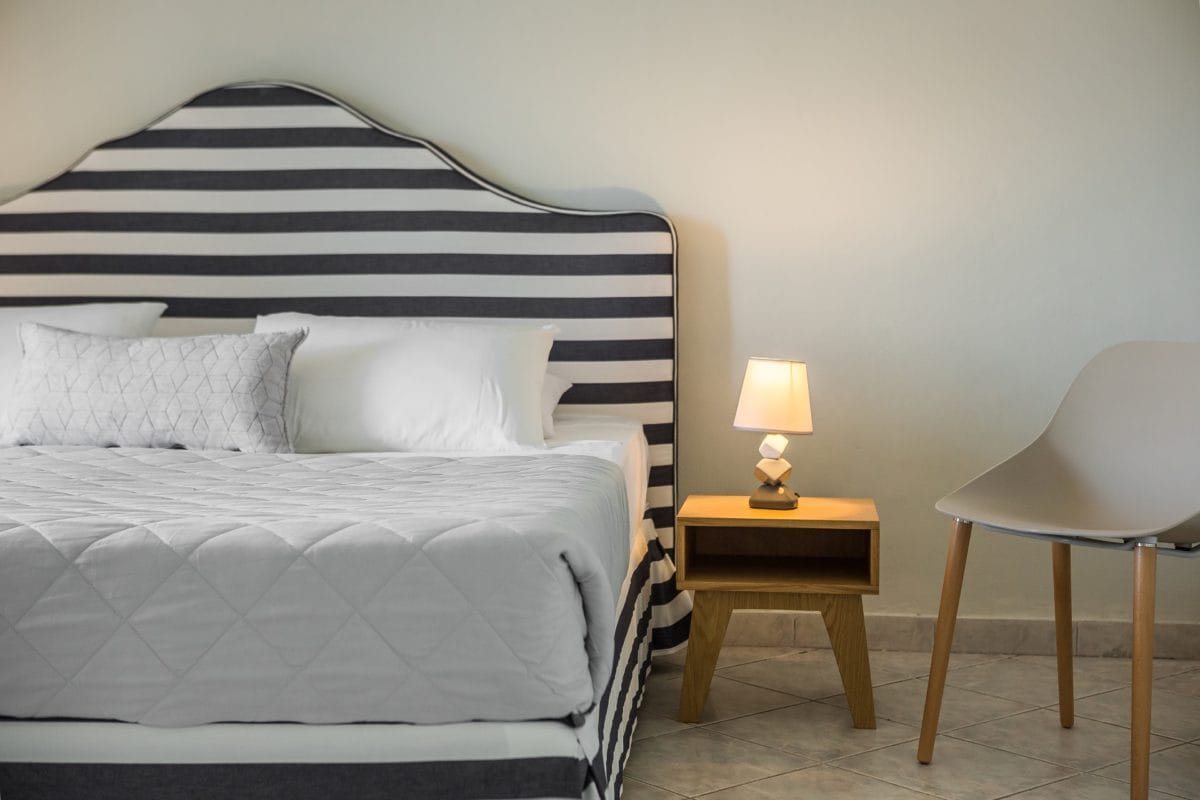 a bed with a lamp and a chair in a room