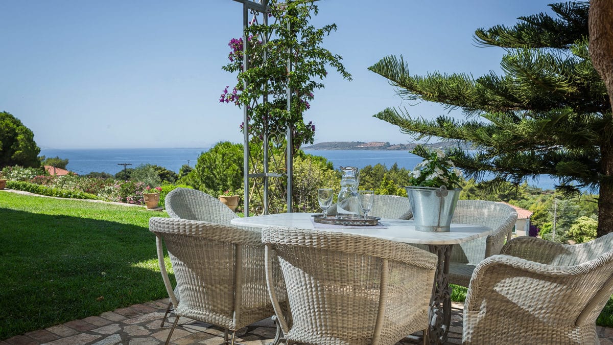 a table with chairs and a plant on it by a body of water