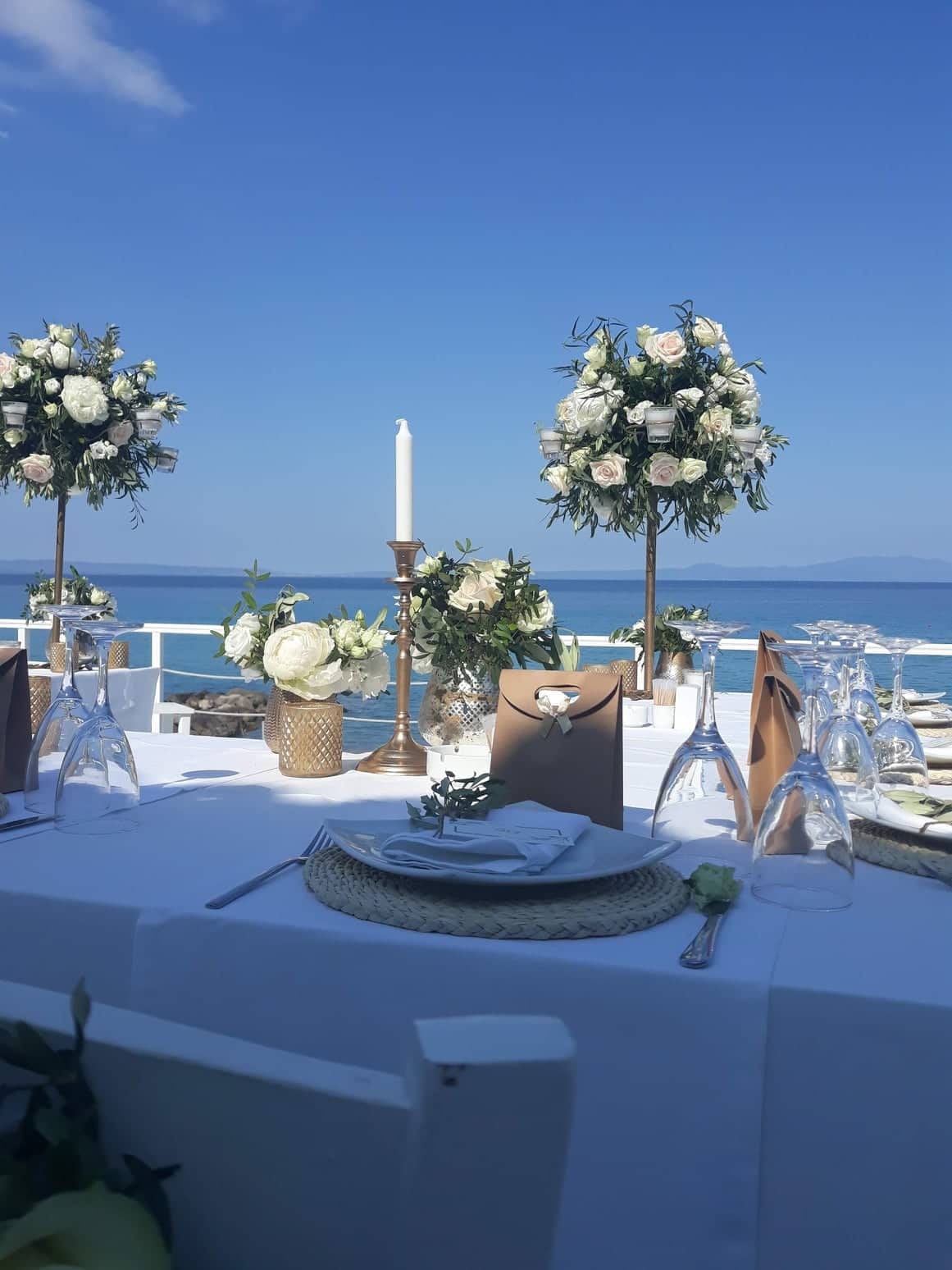a table with flowers and candles on it by a body of water