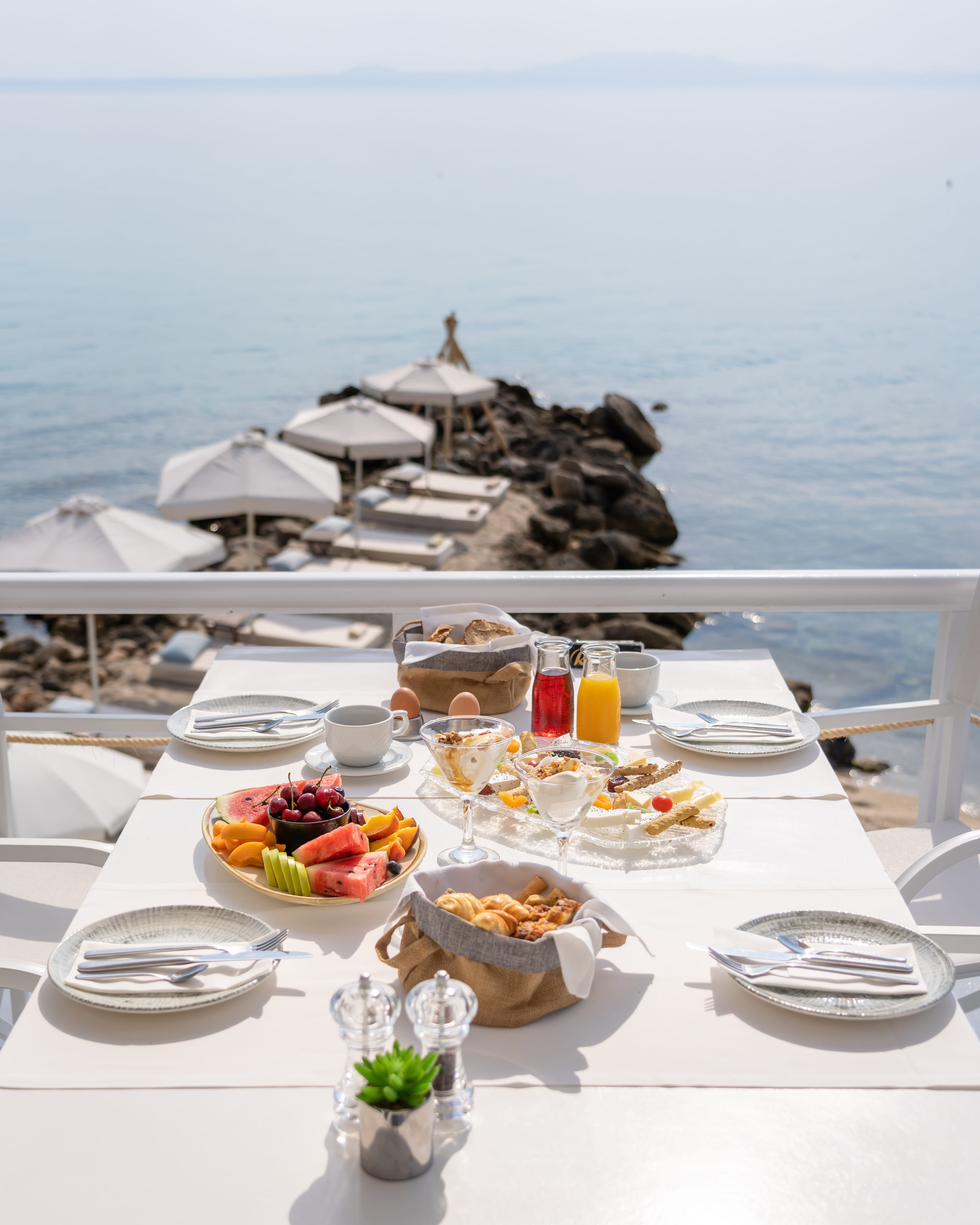 a table with plates and food on it with a body of water in the background