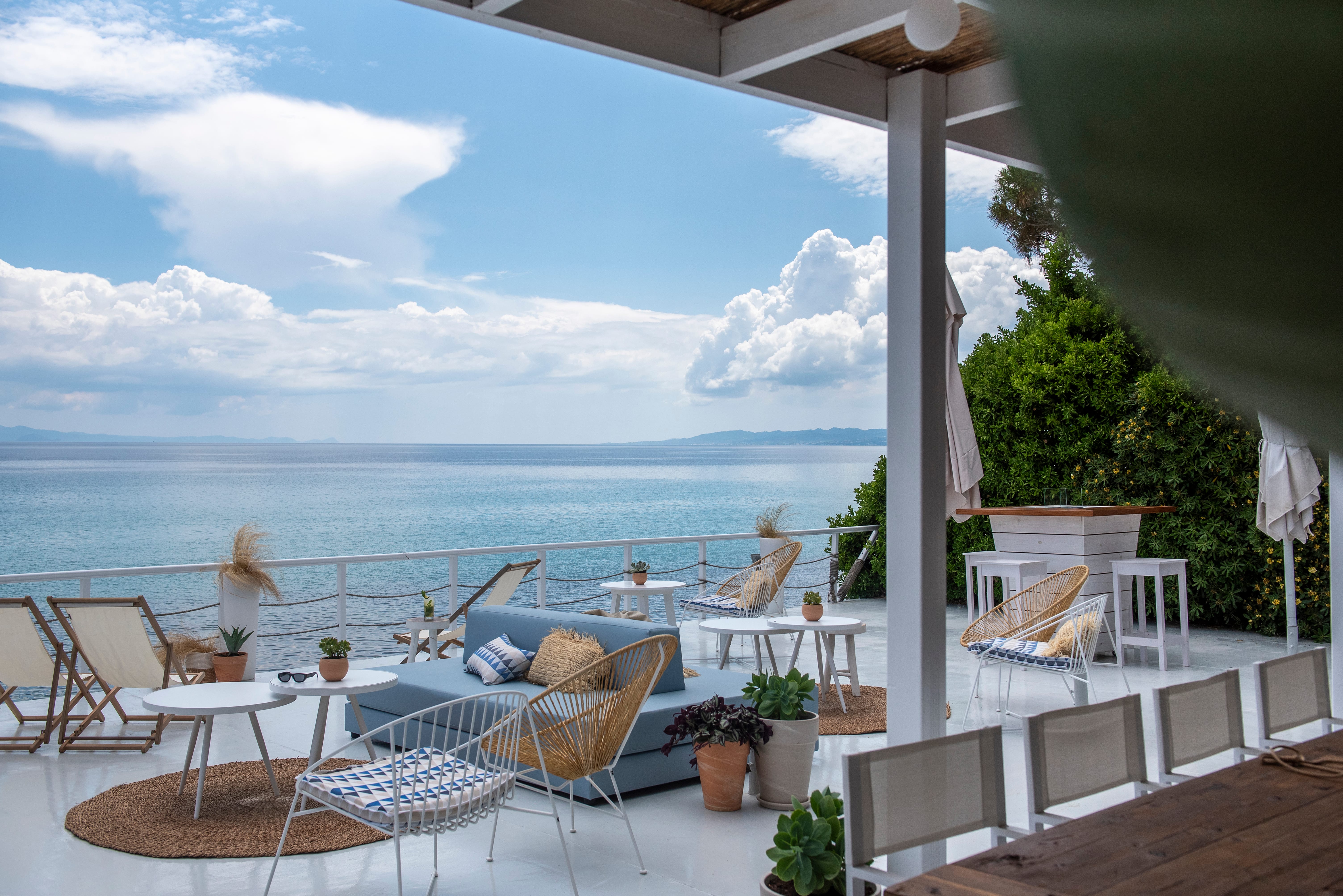 a deck with chairs and tables by the water