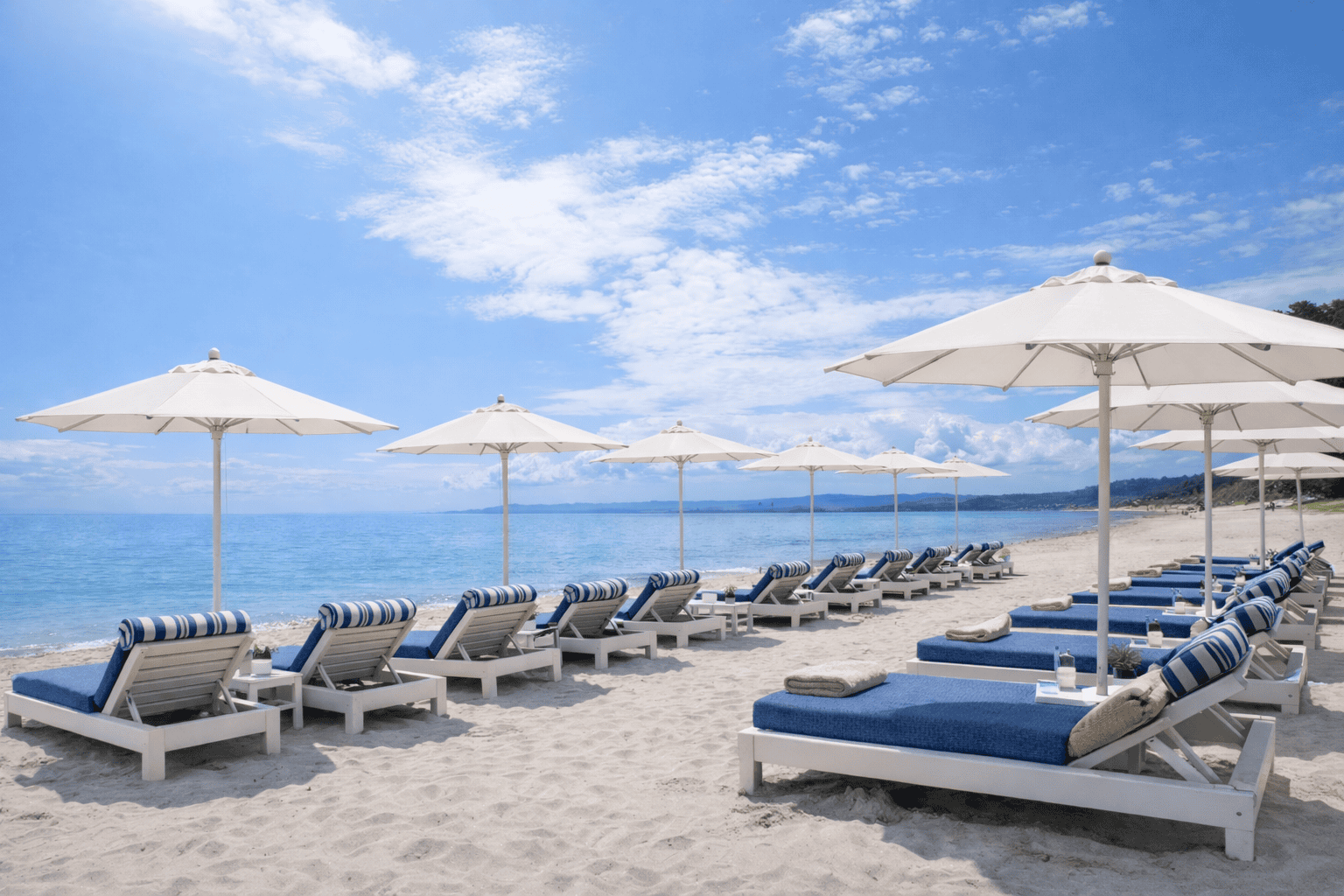 a beach with white chairs and umbrellas