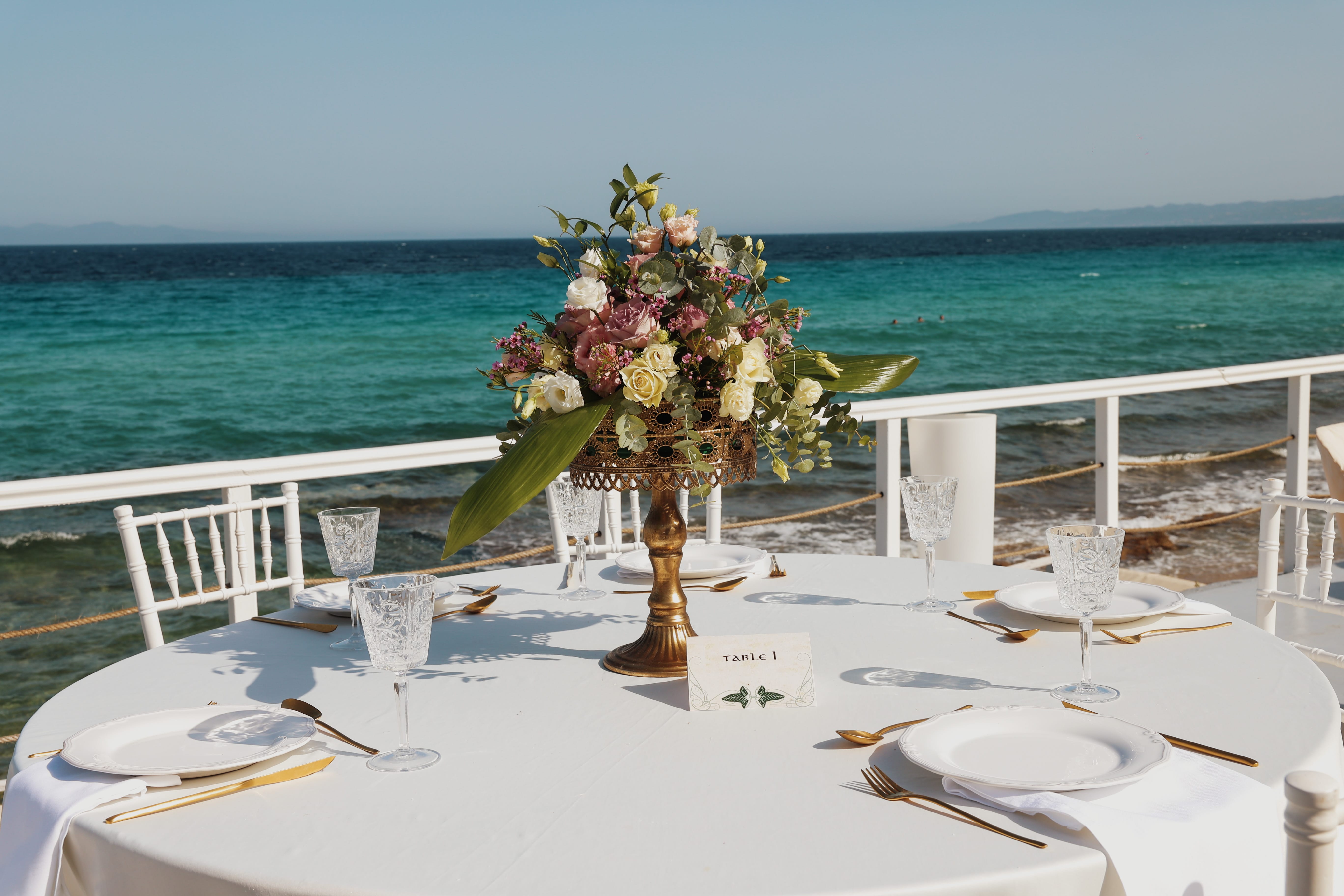 a table with white tables and white chairs with flowers on it