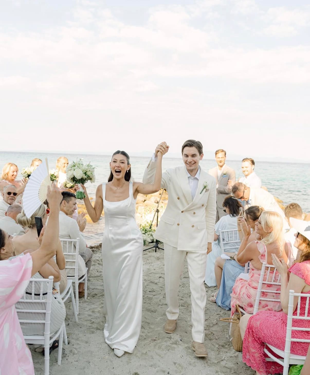 a man and woman holding hands while walking down a beach