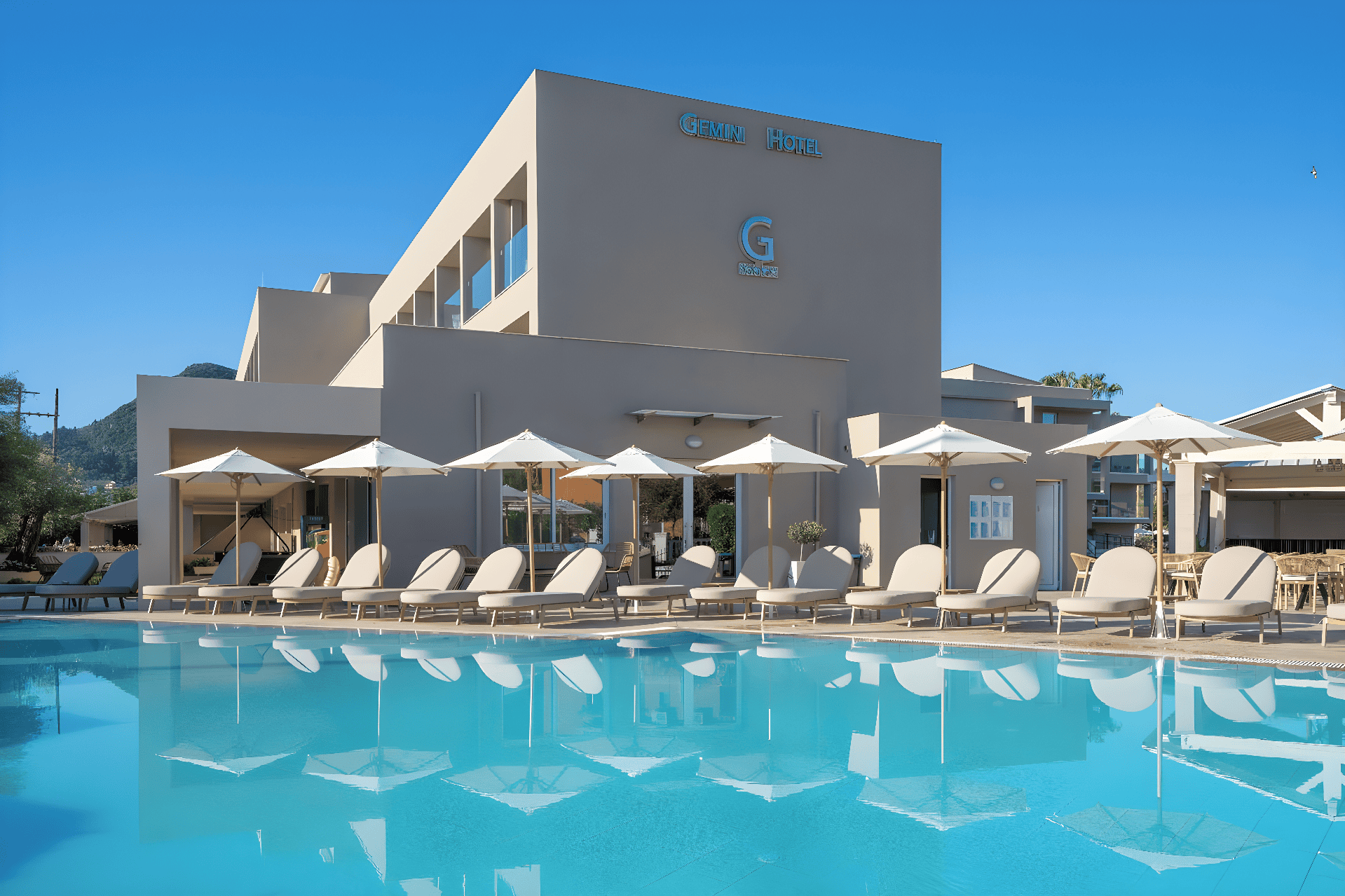 a swimming pool with lounge chairs and umbrellas next to a building