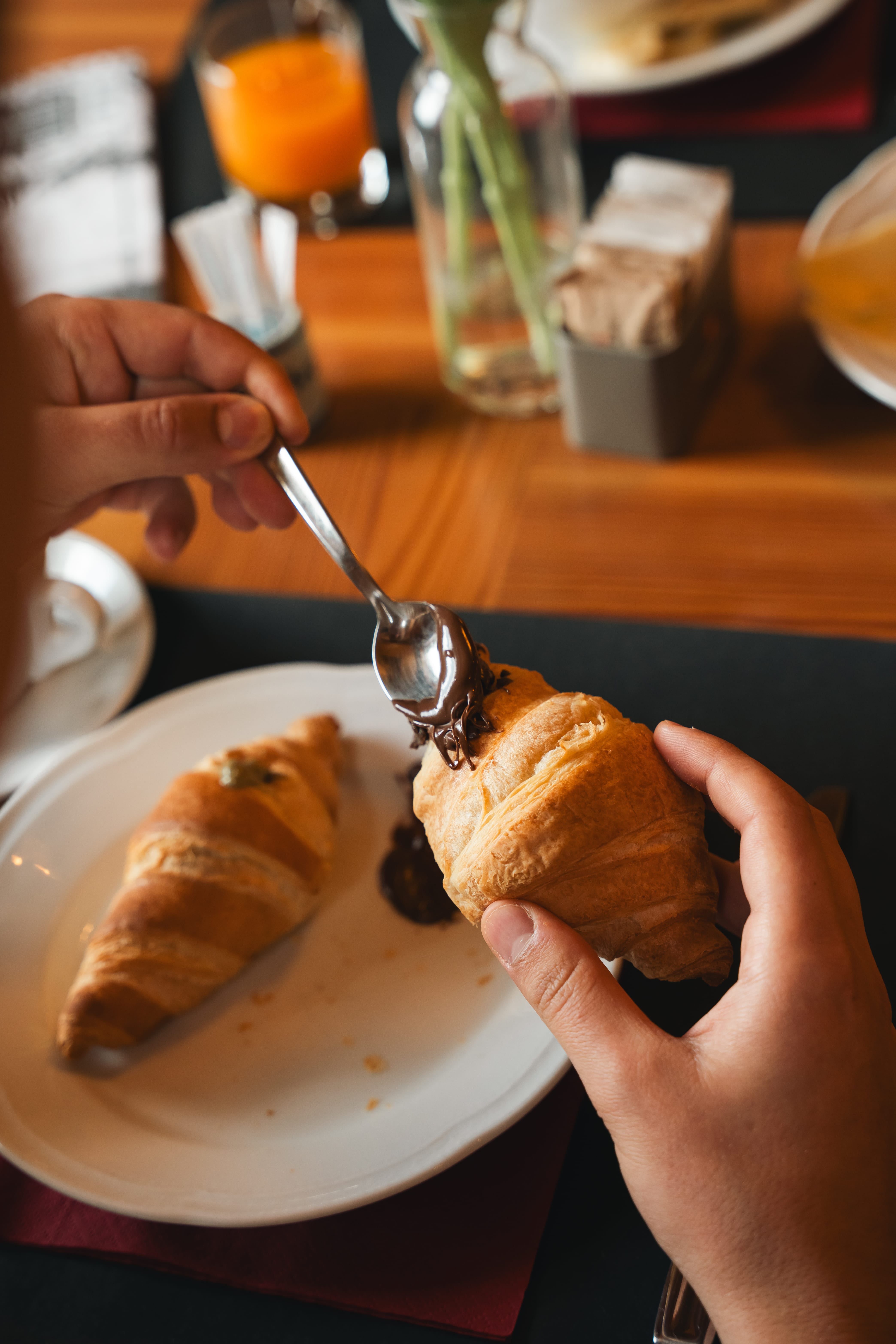 a person spreading chocolate on a croissant
