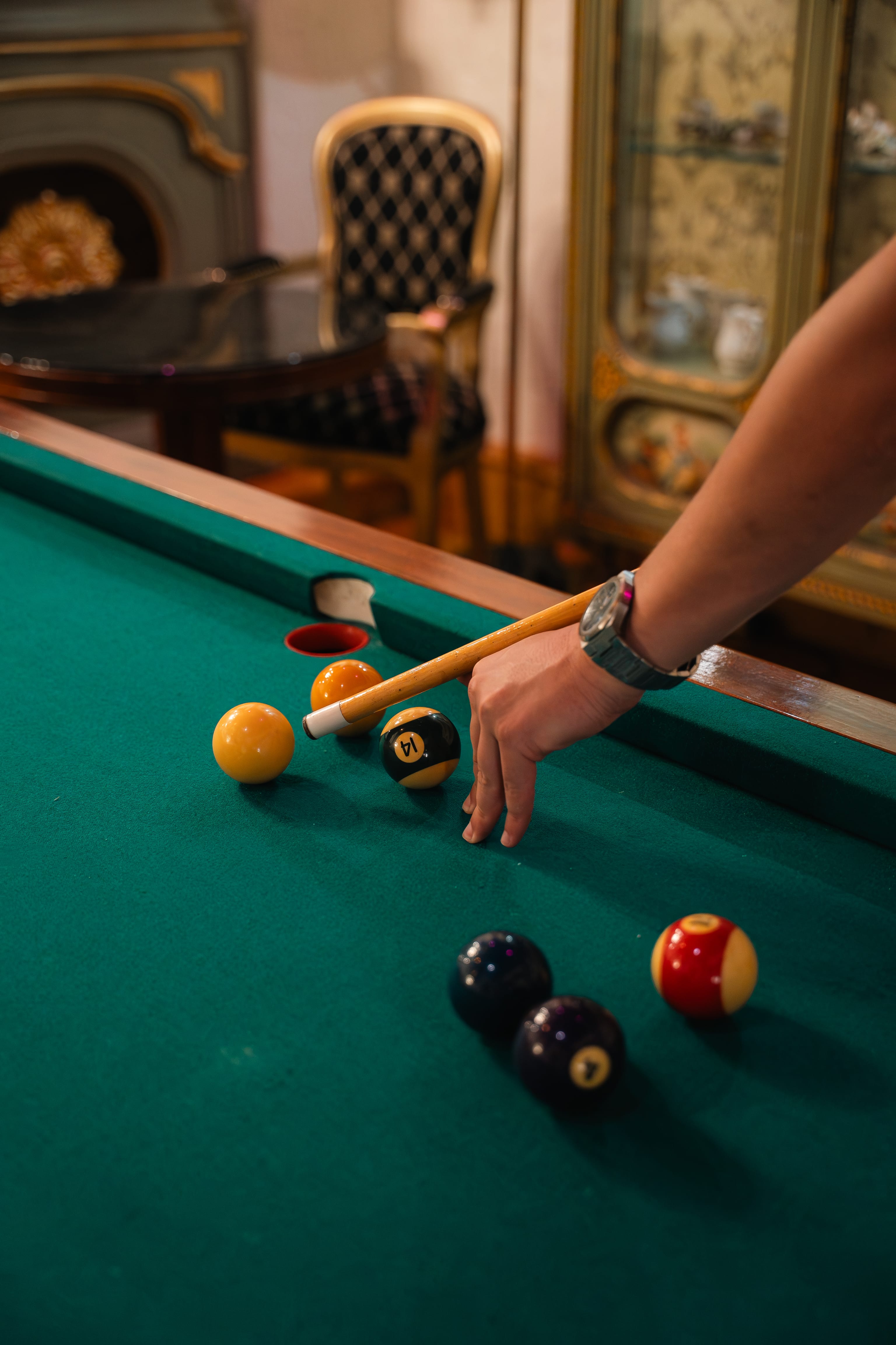 a hand holding a stick to a pool table