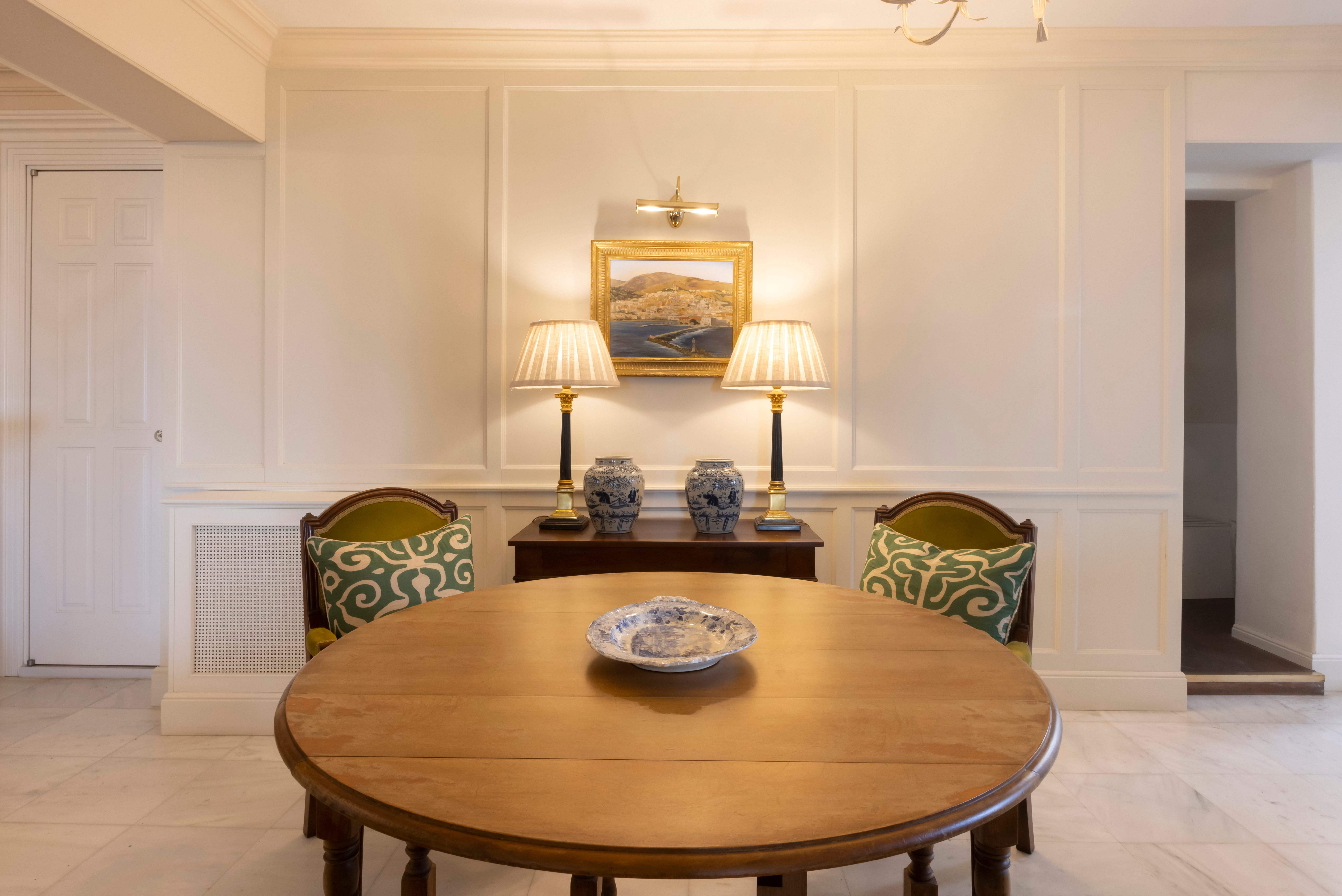 a dining room table with a lamp and a painting on the wall