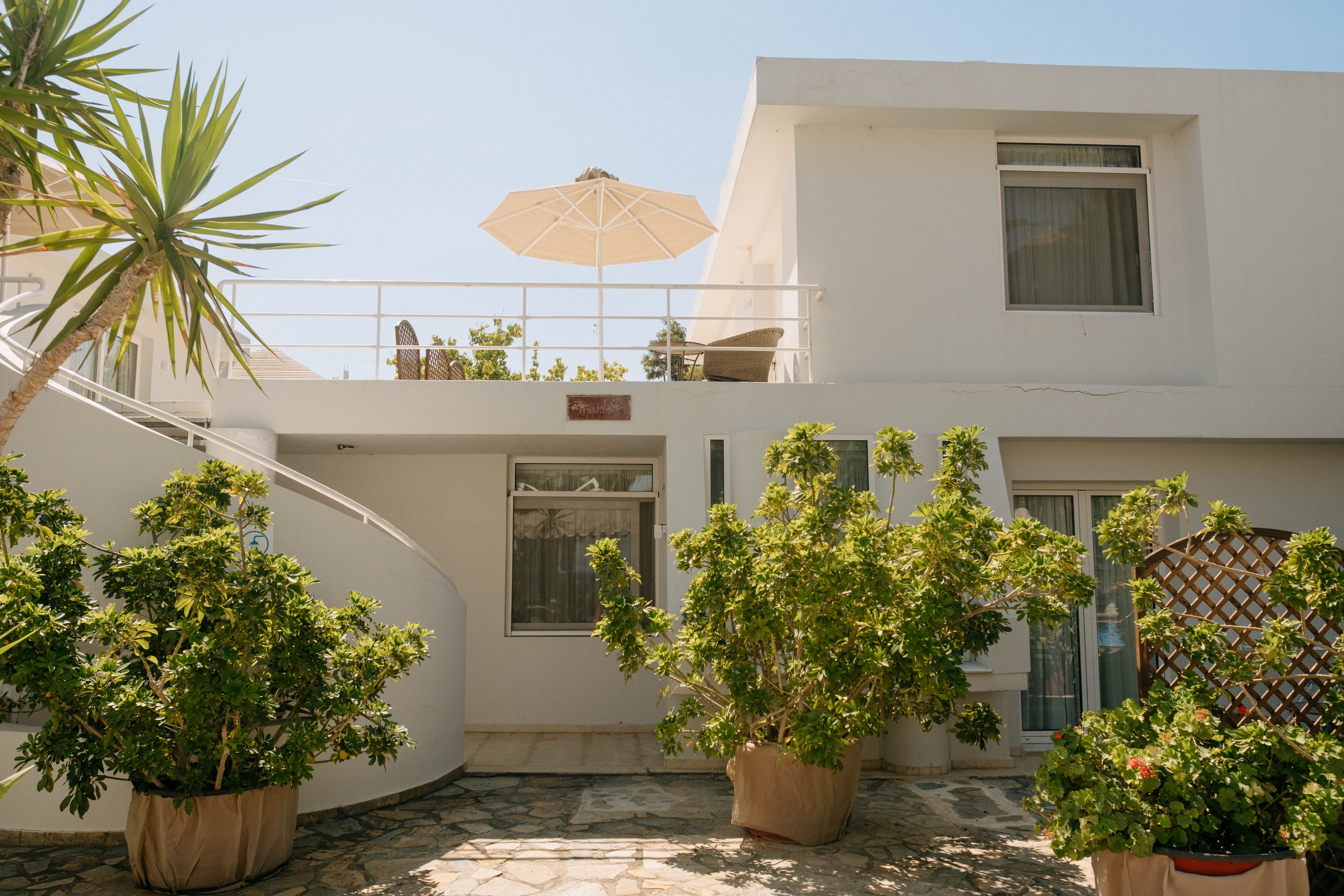 a patio with potted plants and a large umbrella