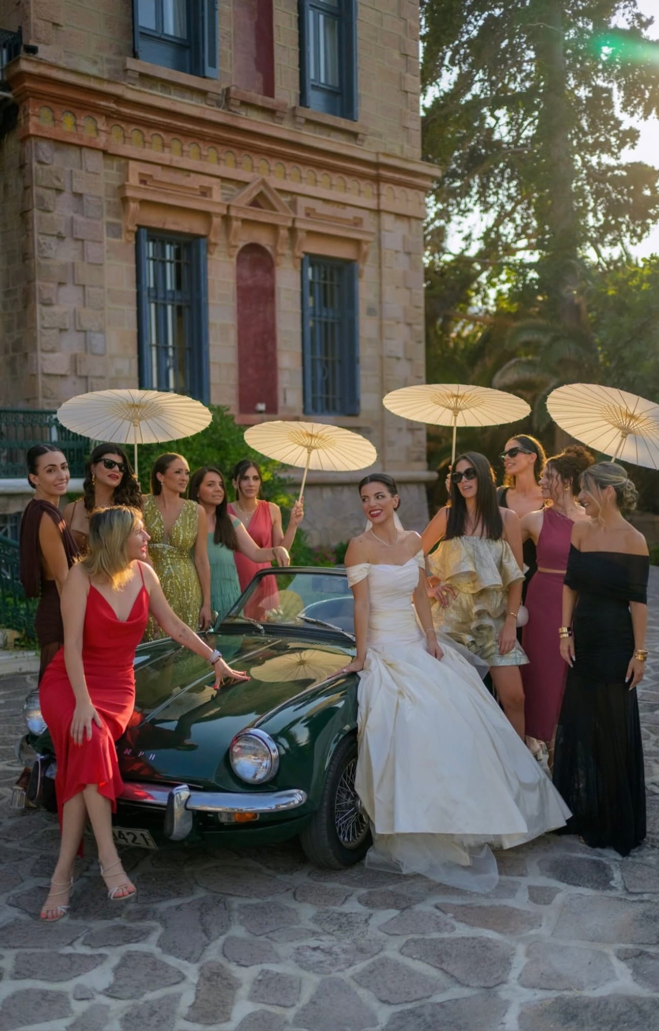 a group of people in dresses and dresses standing next to a car
