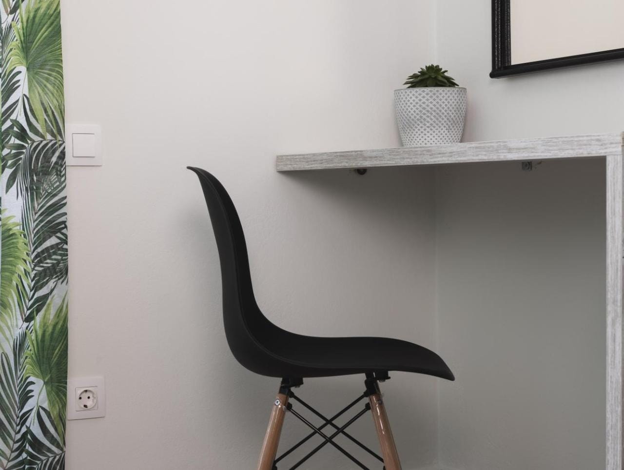 a black chair in front of a white shelf with a plant