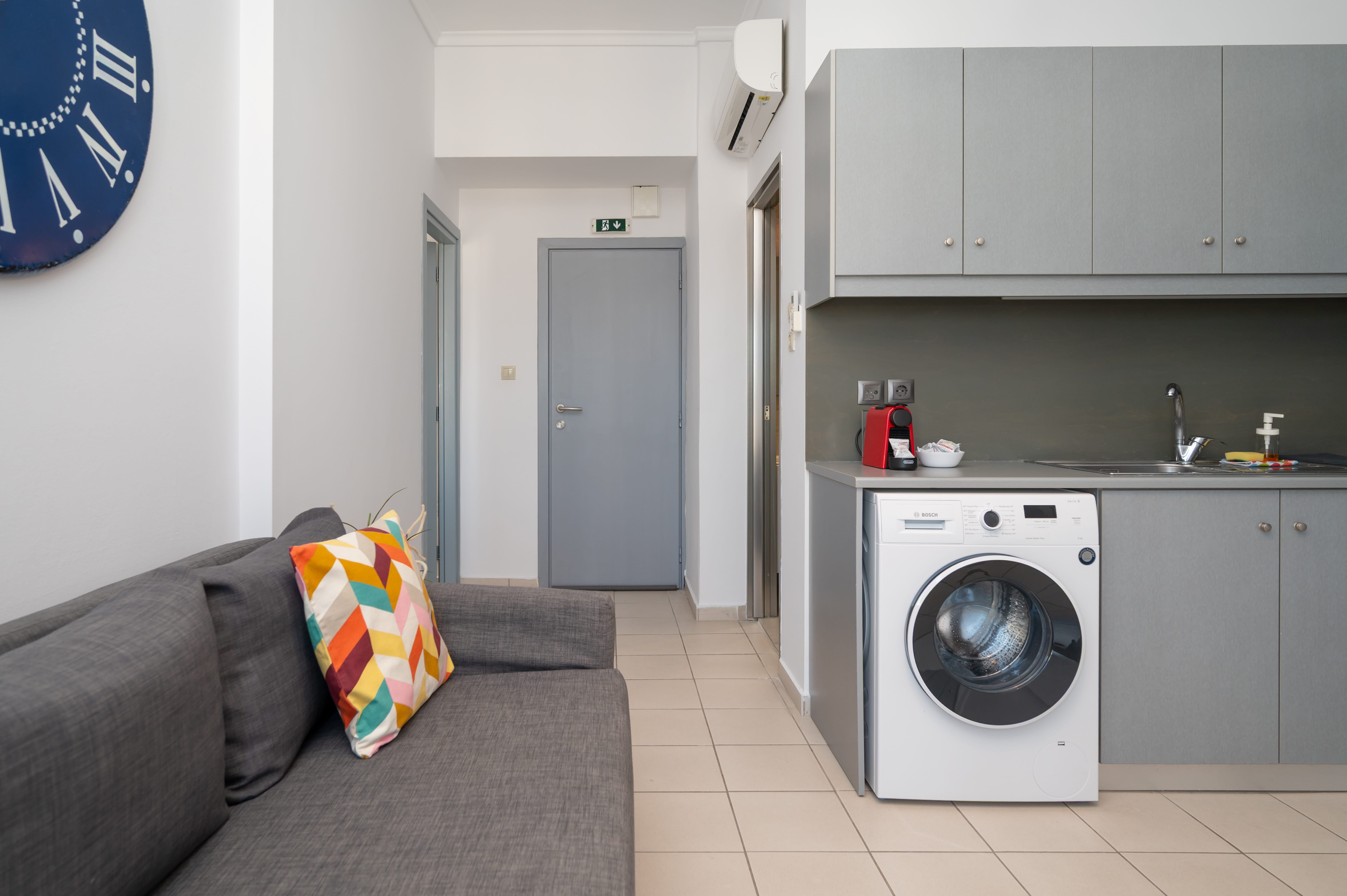 a room with a washing machine and a grey couch