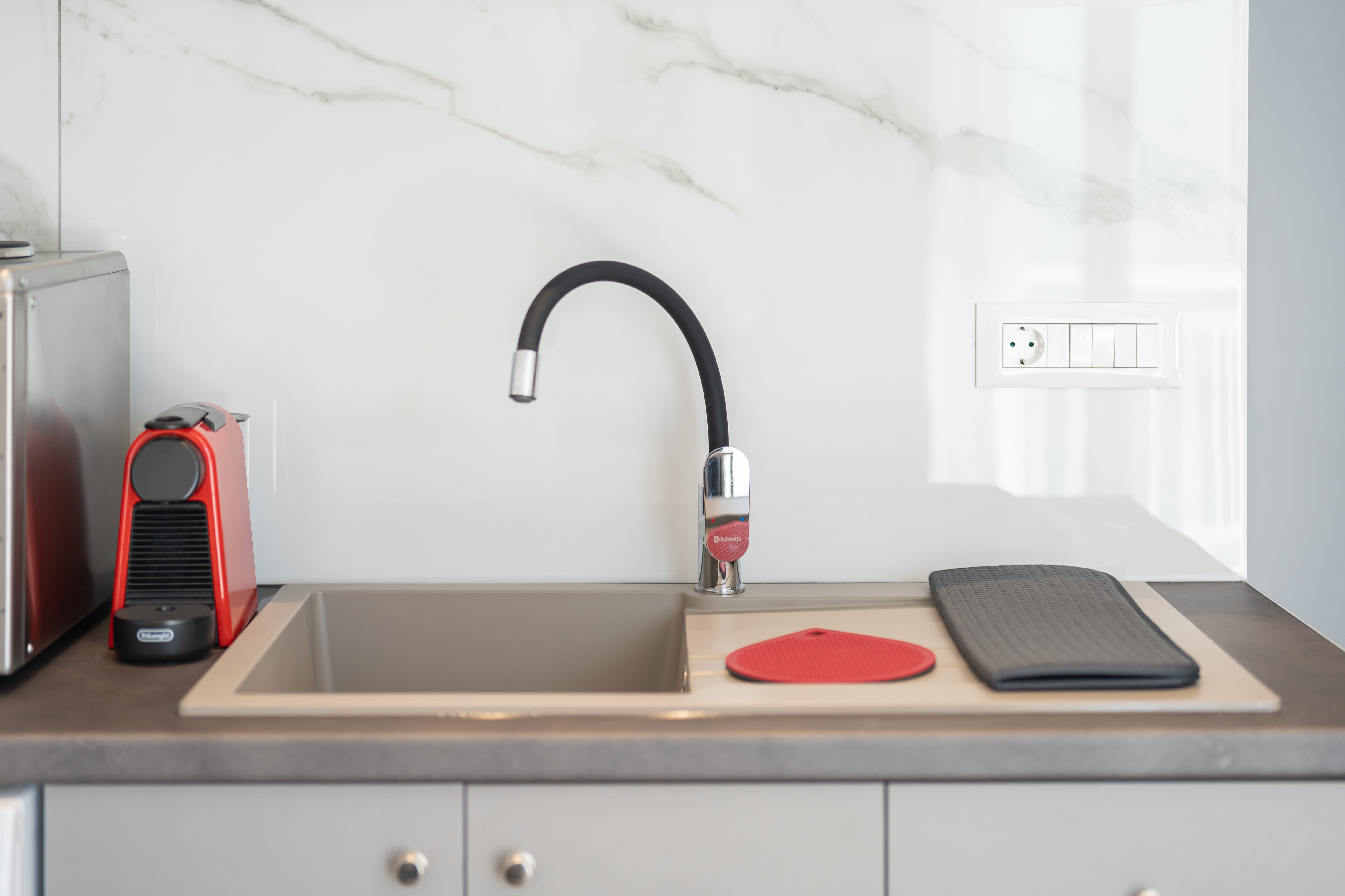 a sink with a faucet and a red and black pad on a counter