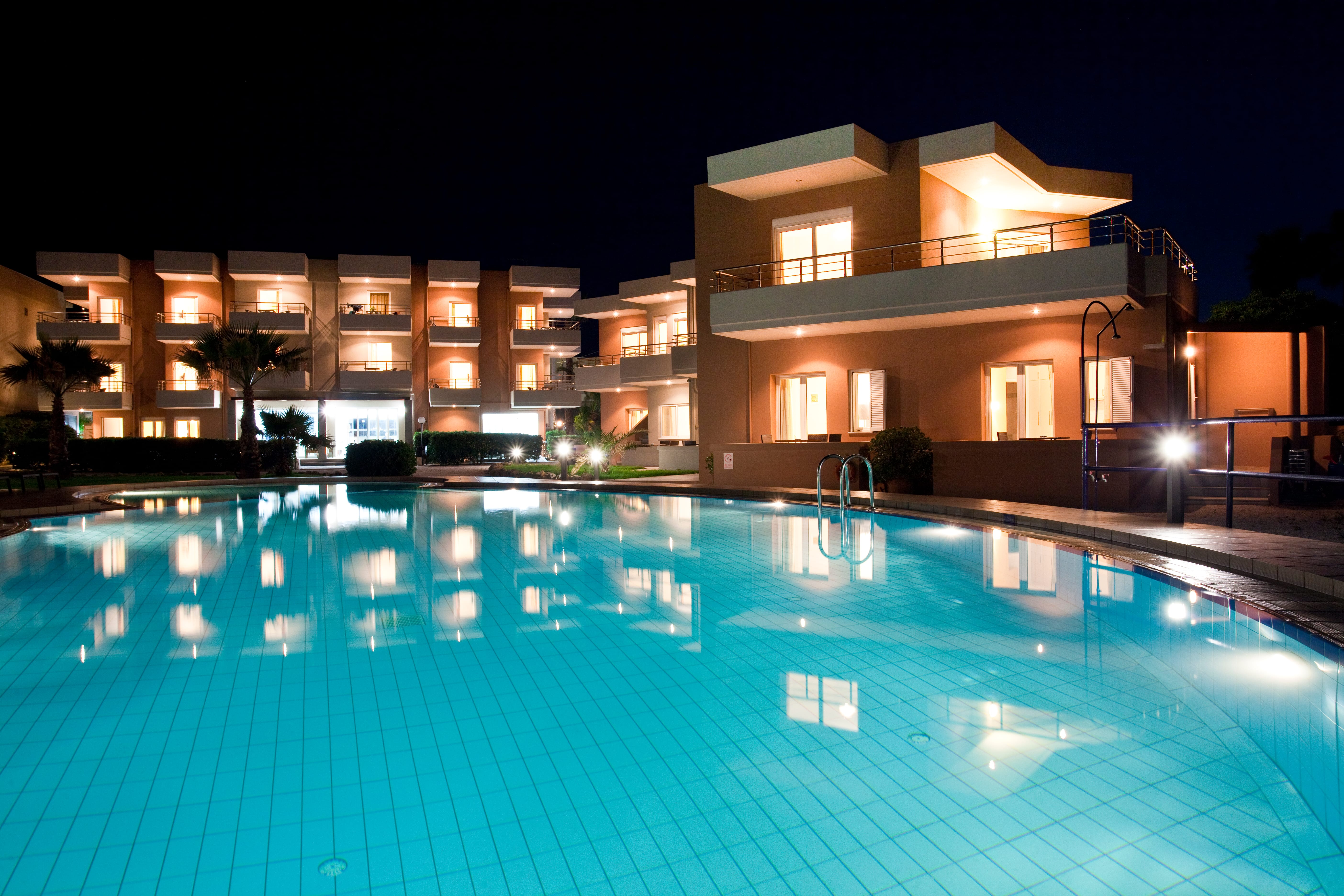 a swimming pool in front of a building at night
