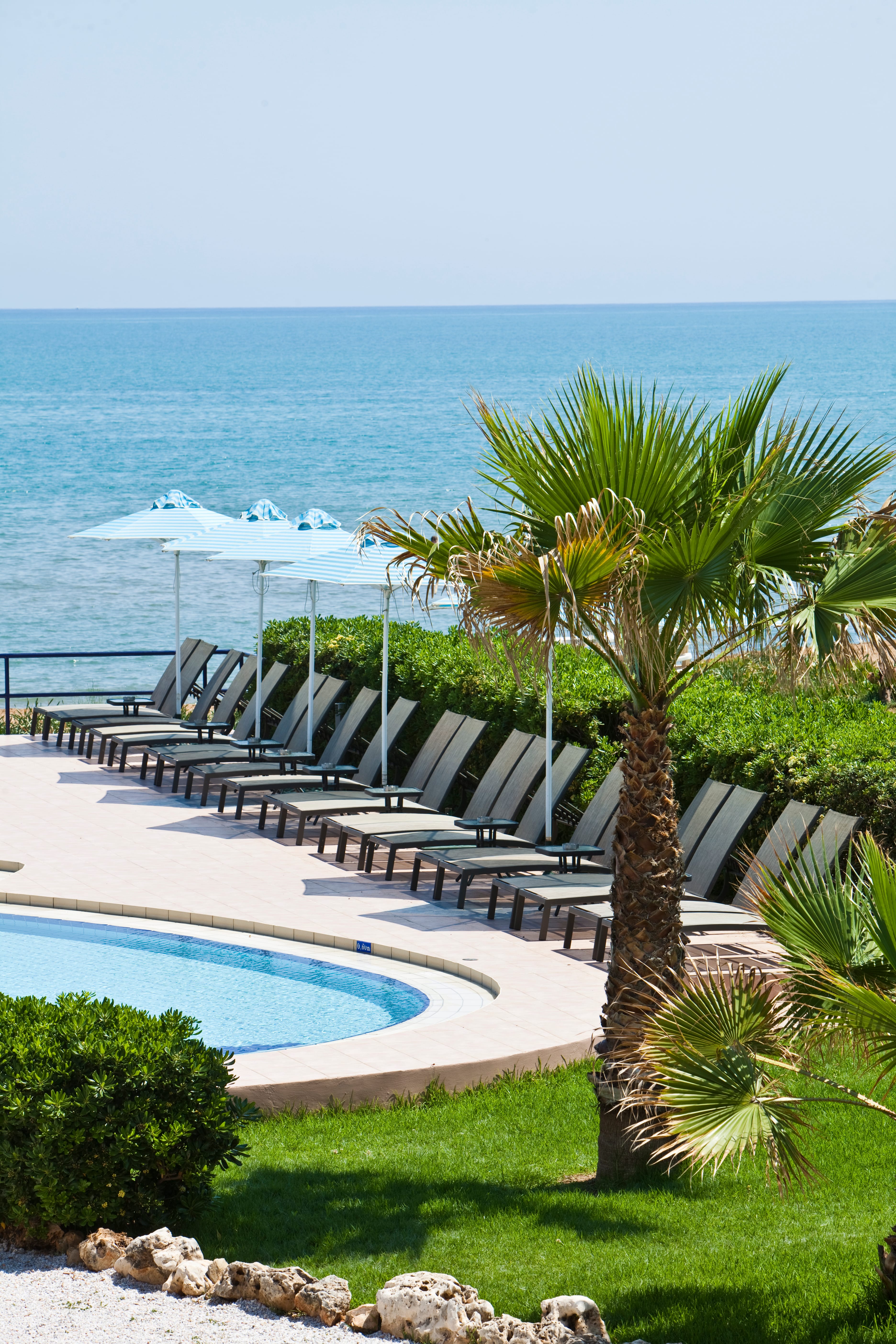 a pool and lounge chairs by a beach
