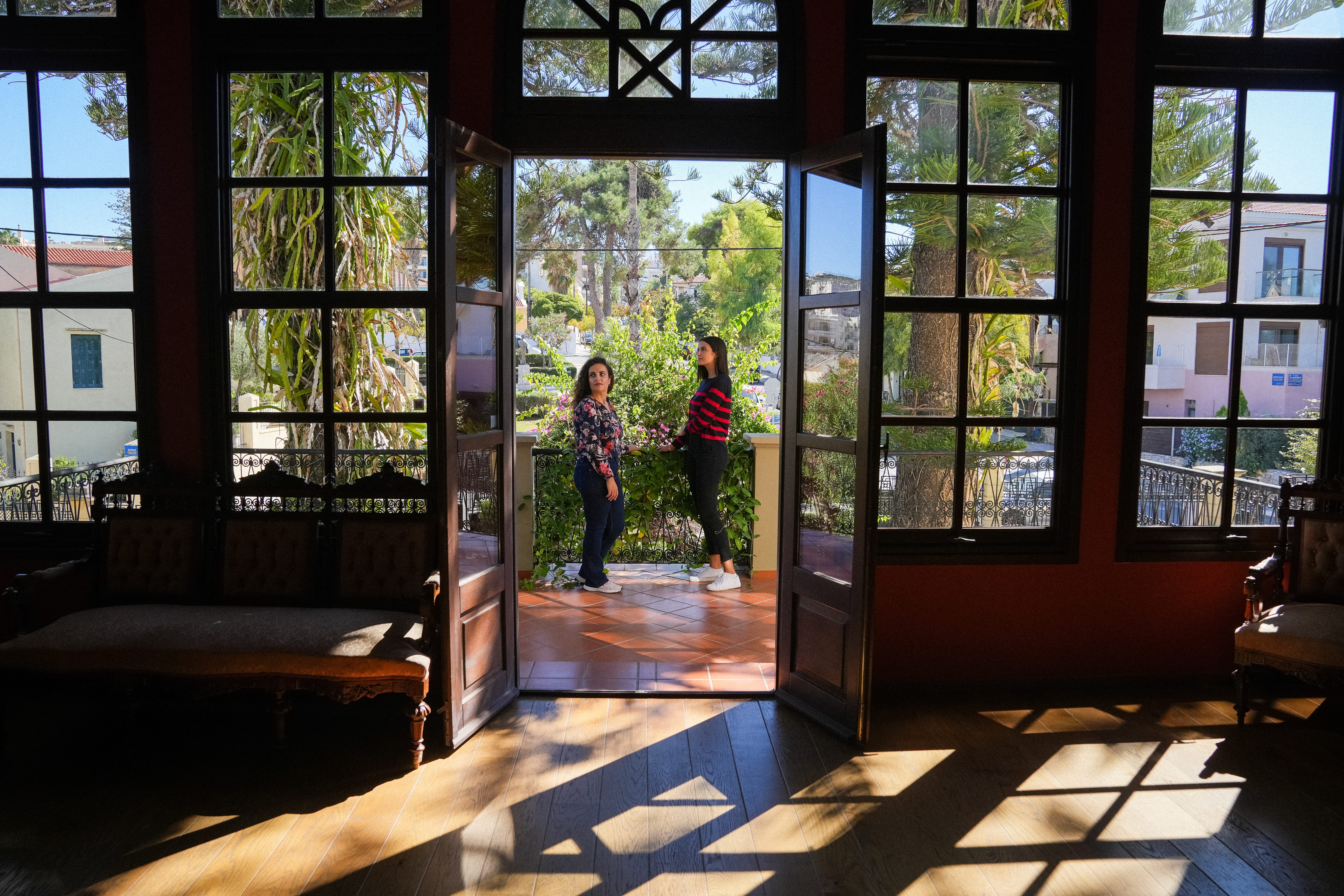 a couple of people standing in a room with large windows