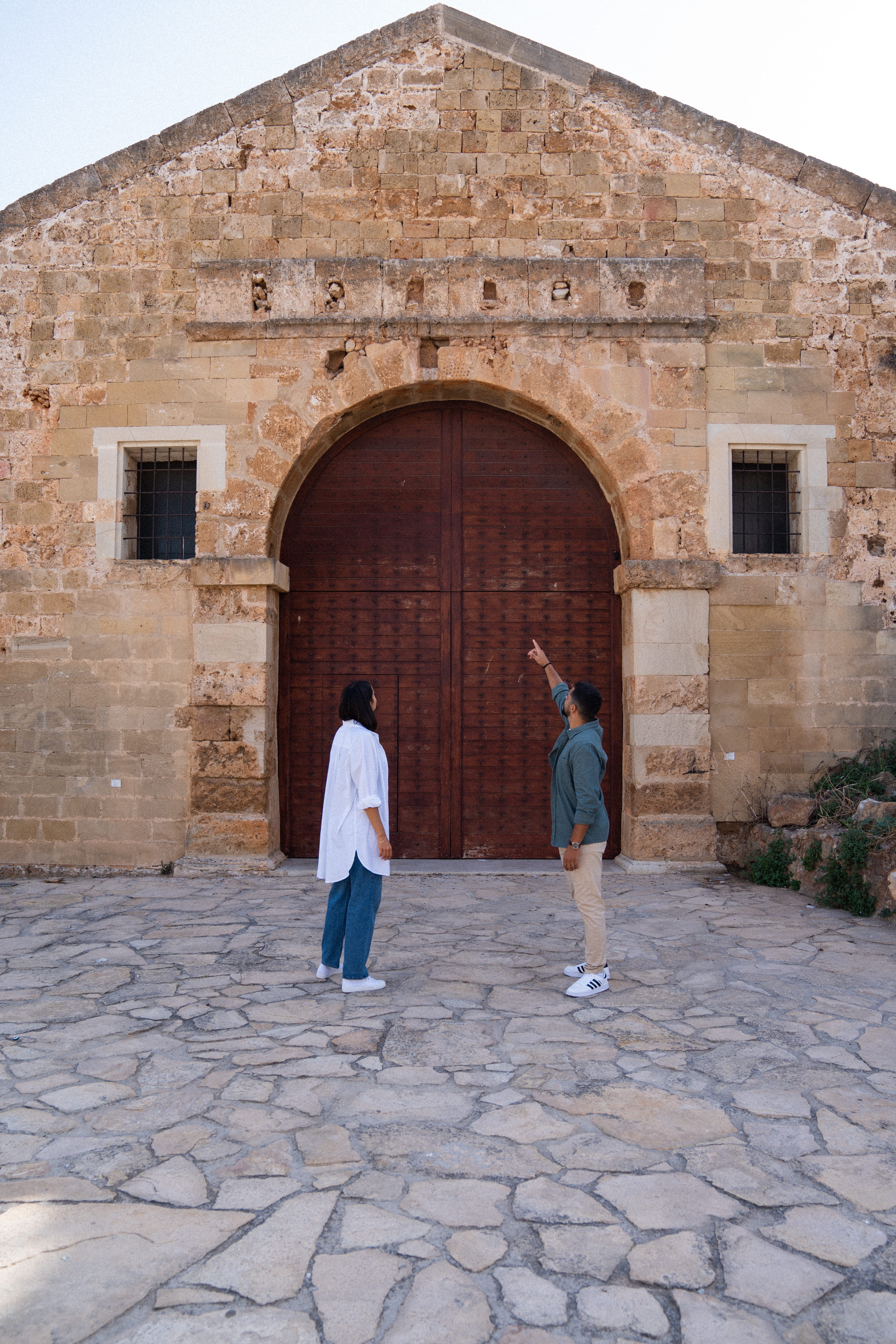 a couple of people standing in front of a building with a large arched doorway