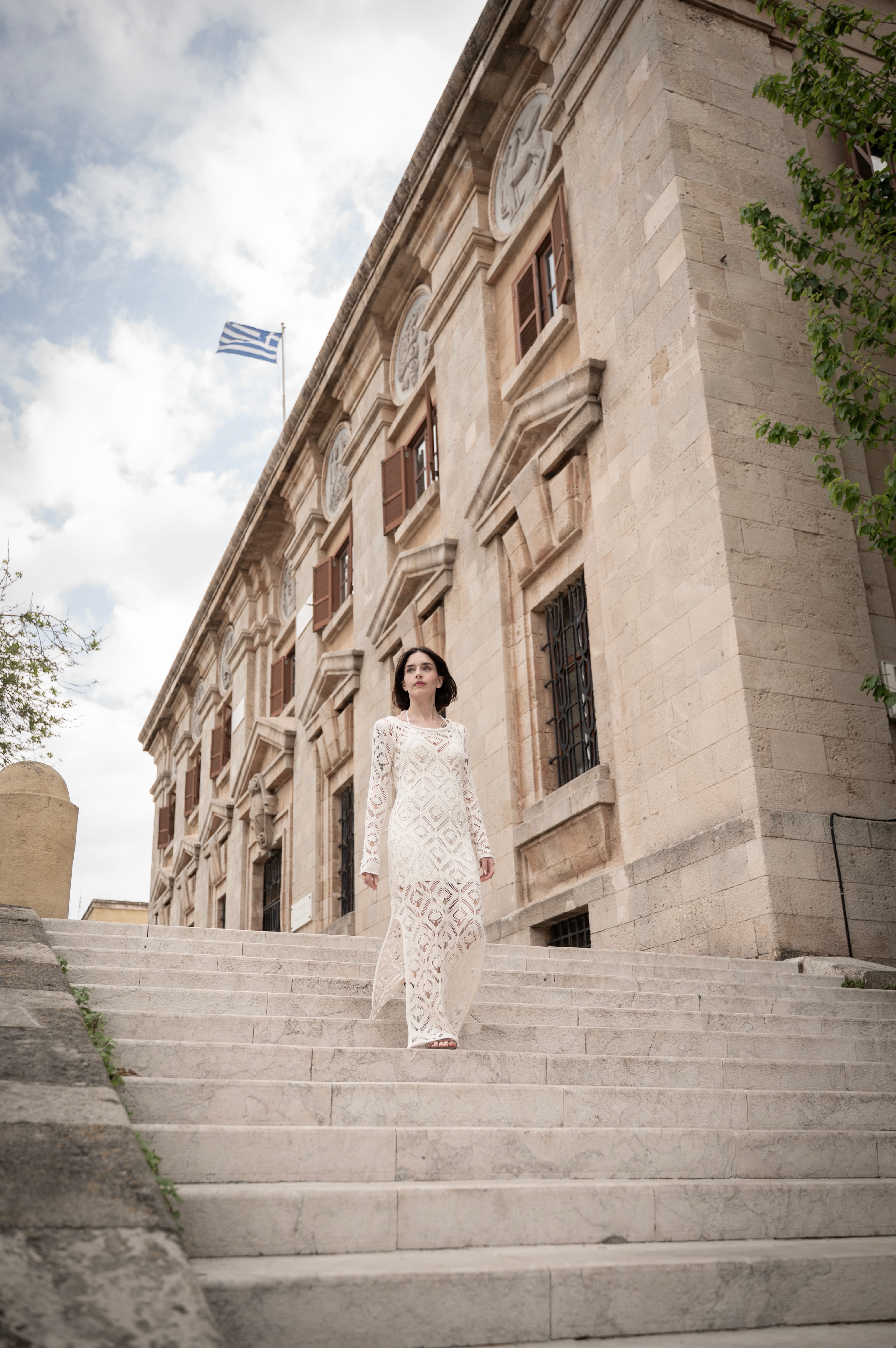 a person in a white dress standing on stairs outside of a building