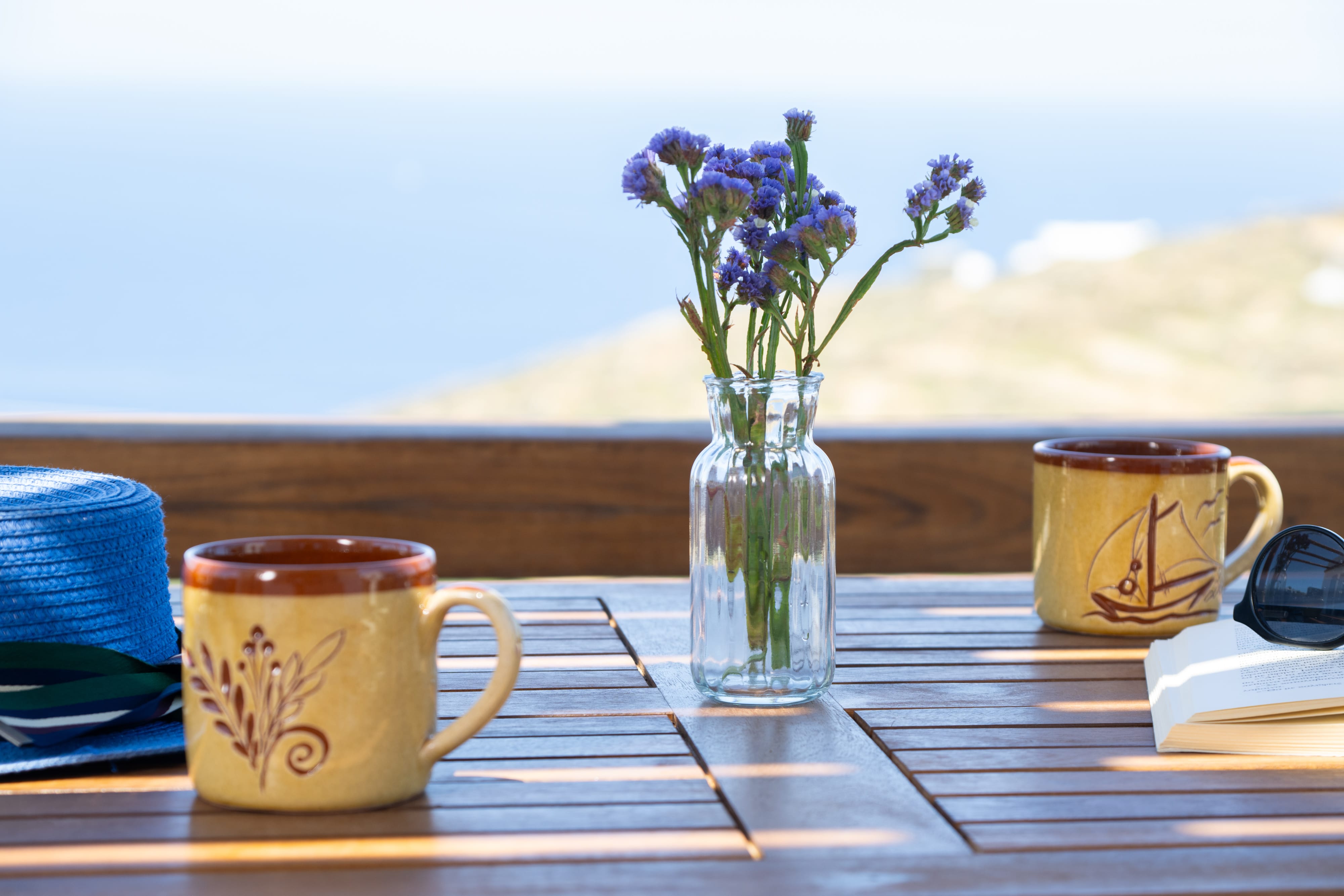 a vase of flowers and two cups on a table