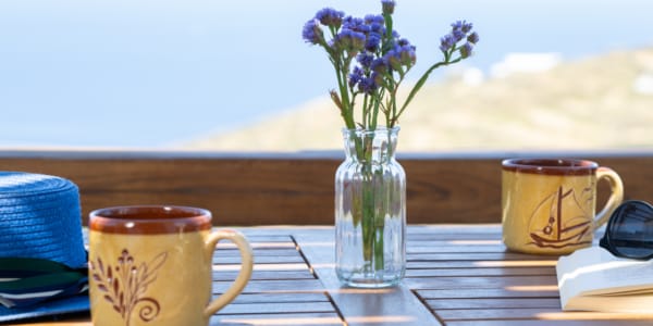 a vase of flowers and two cups on a table