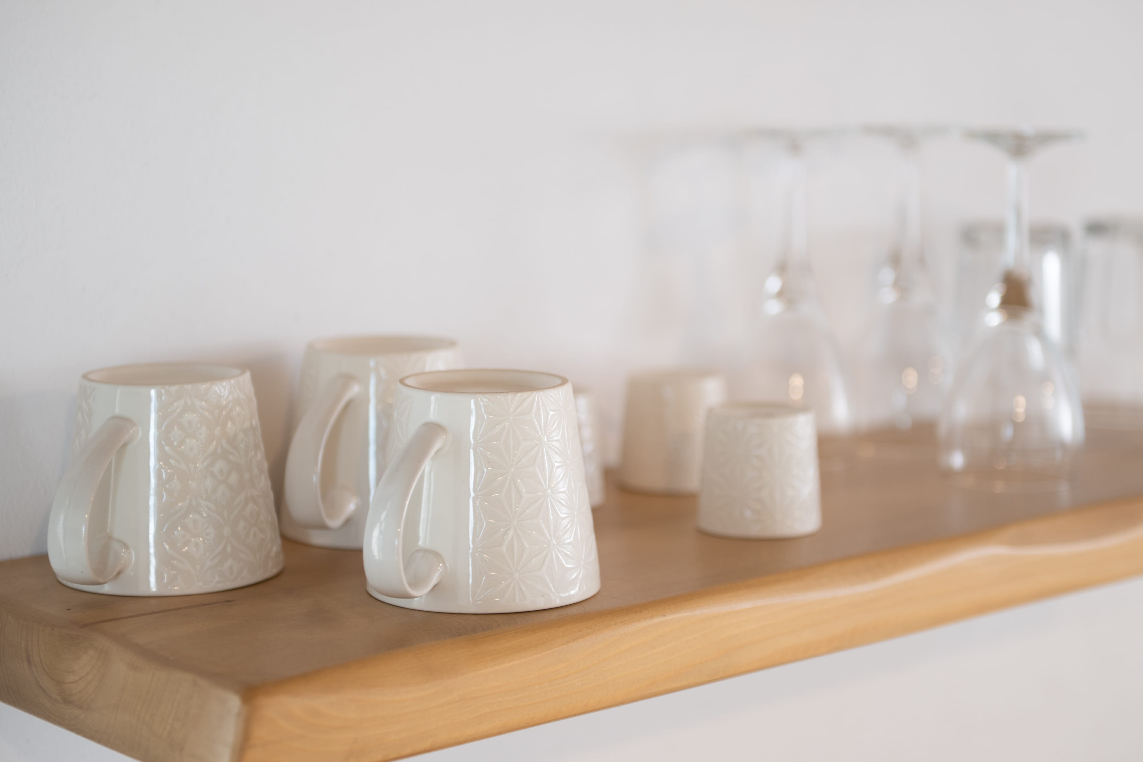a shelf with white mugs and glasses