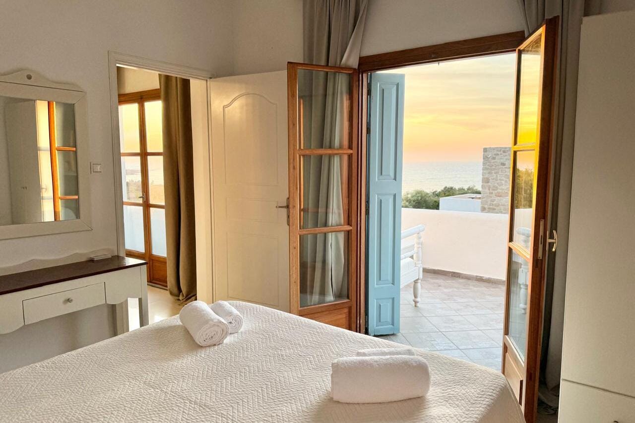 a bedroom with a door open to the ocean
