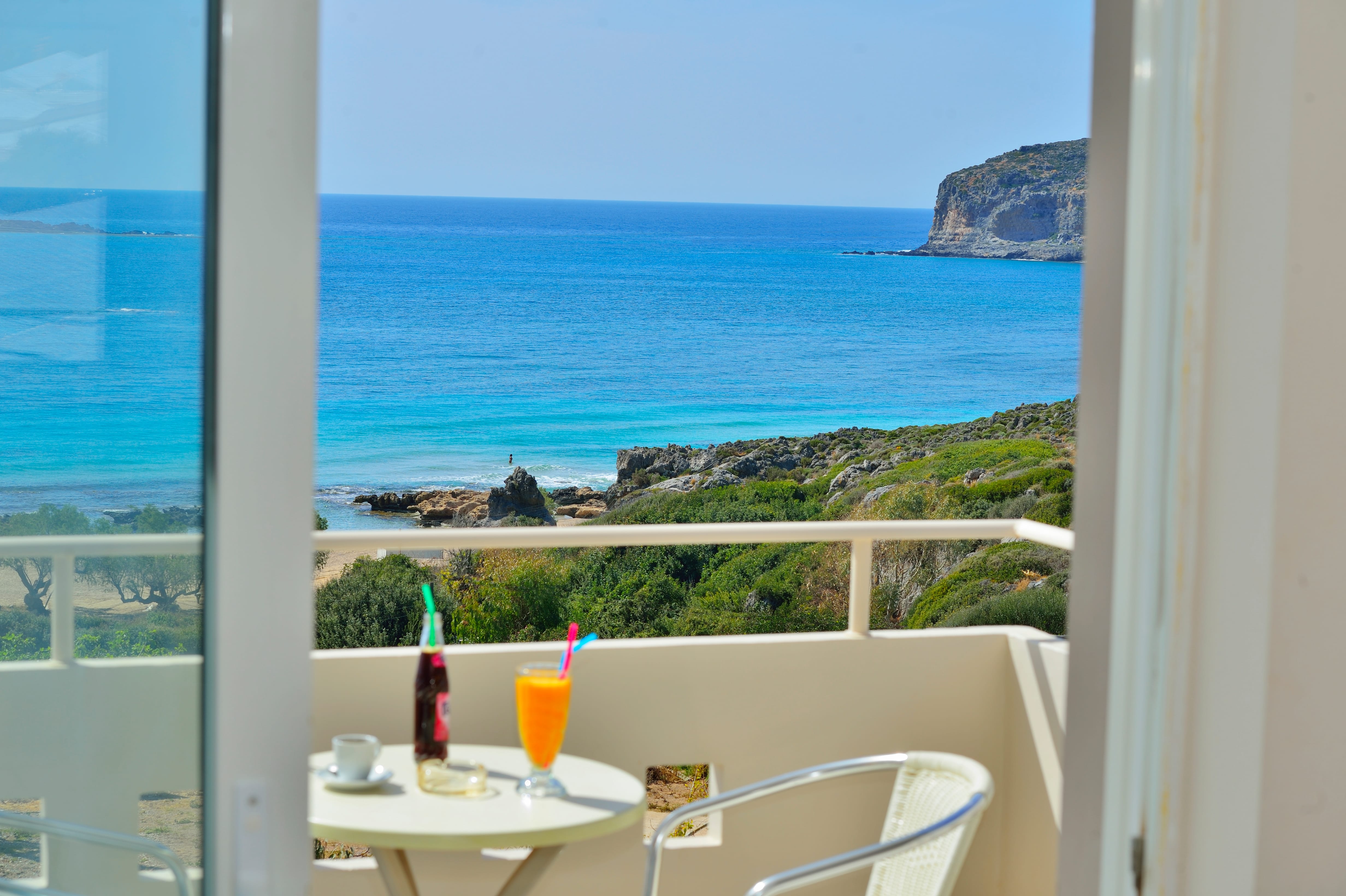 a table and chairs by a window overlooking a beach