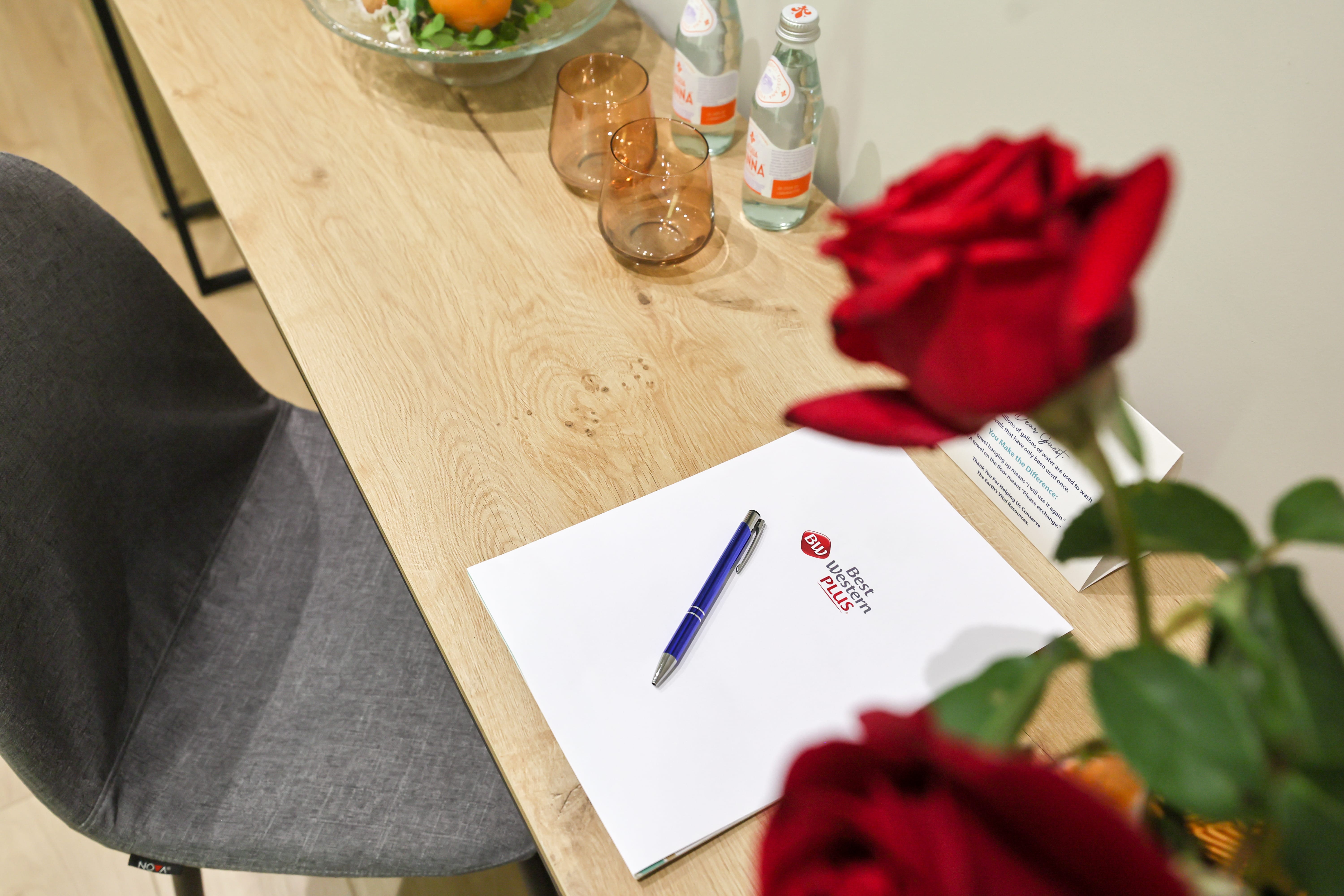 a red rose and a pen on a table
