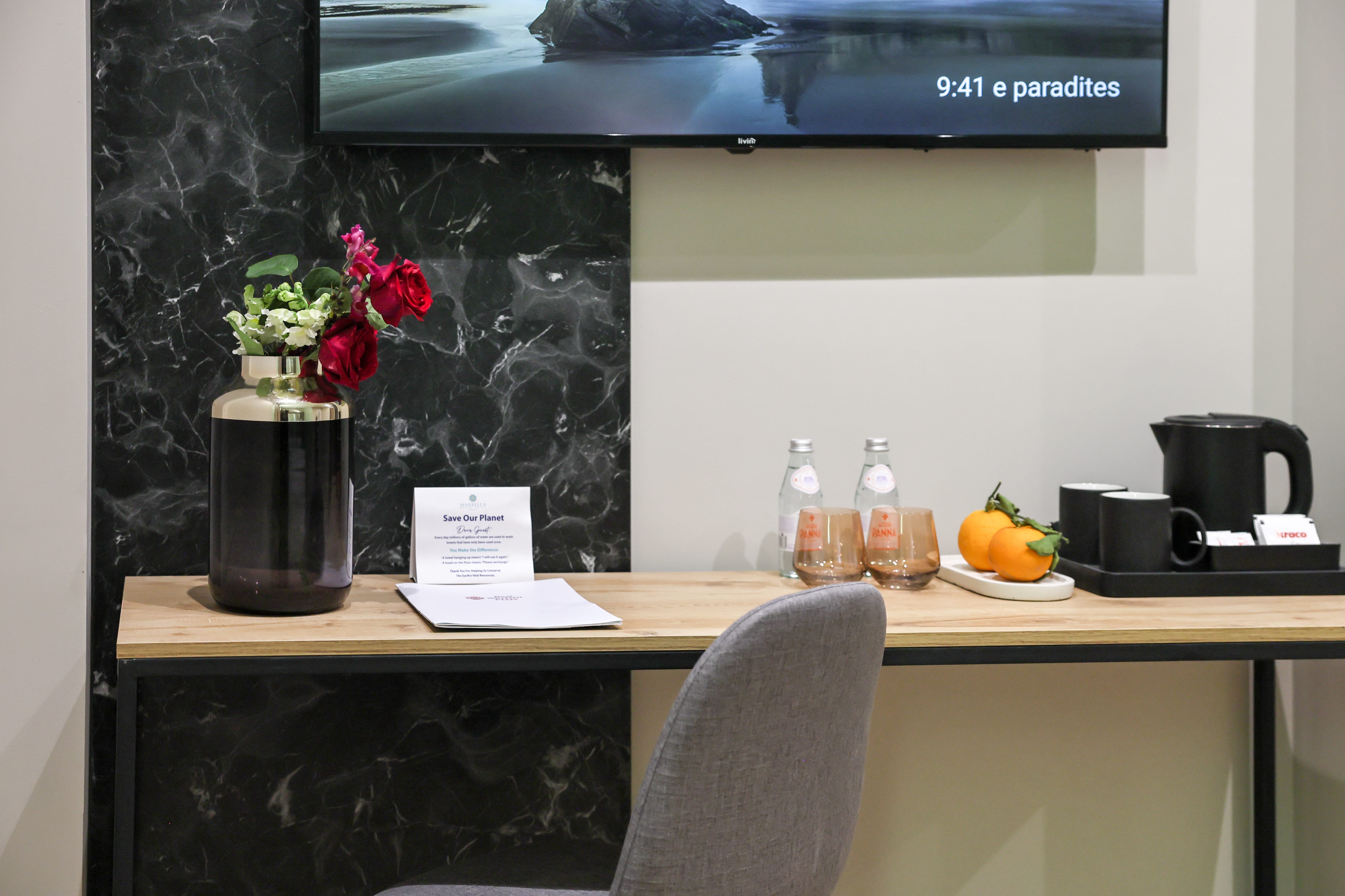 a desk with a vase of flowers and a television above it
