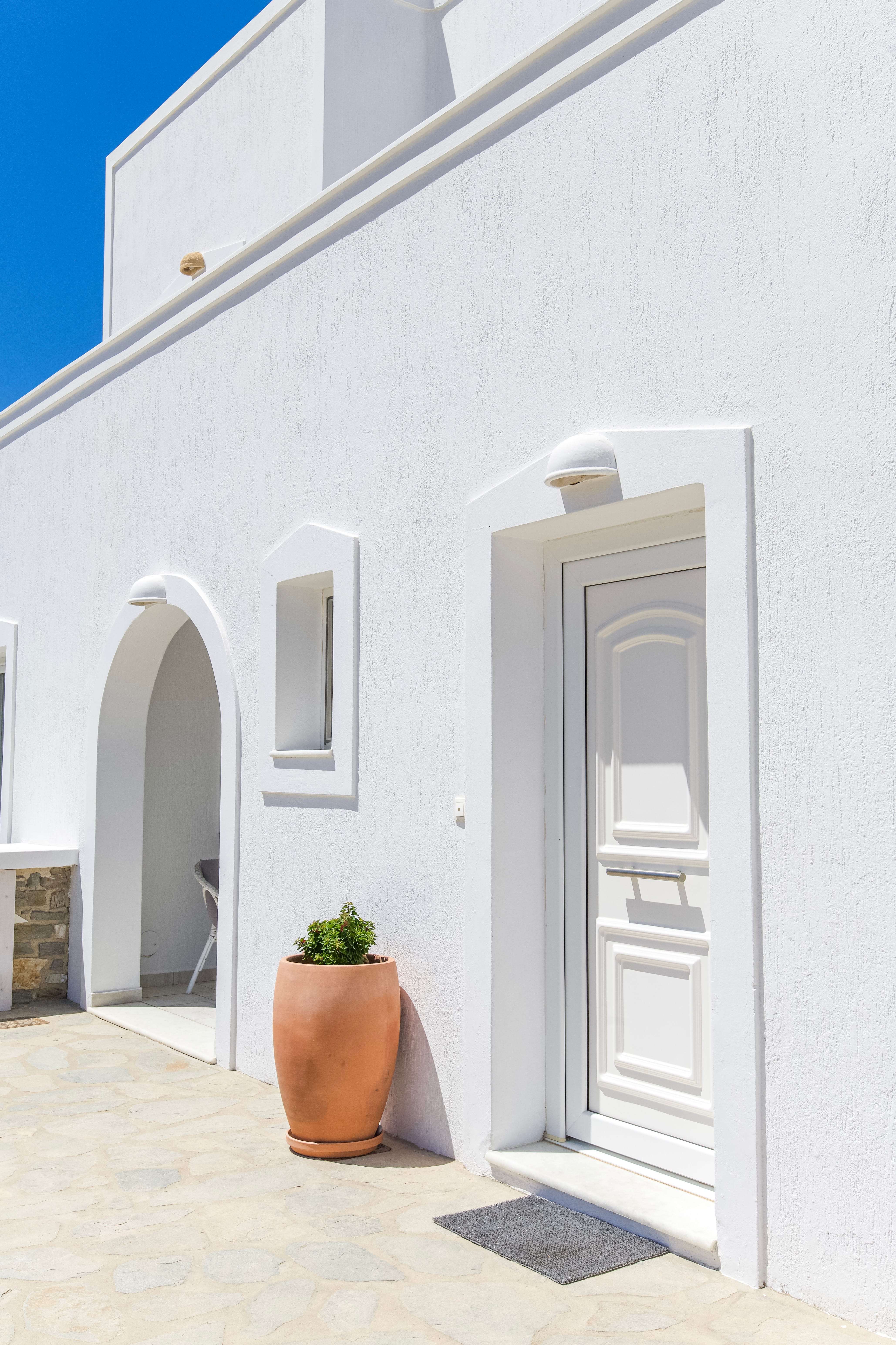 a white building with a large white door and a potted plant