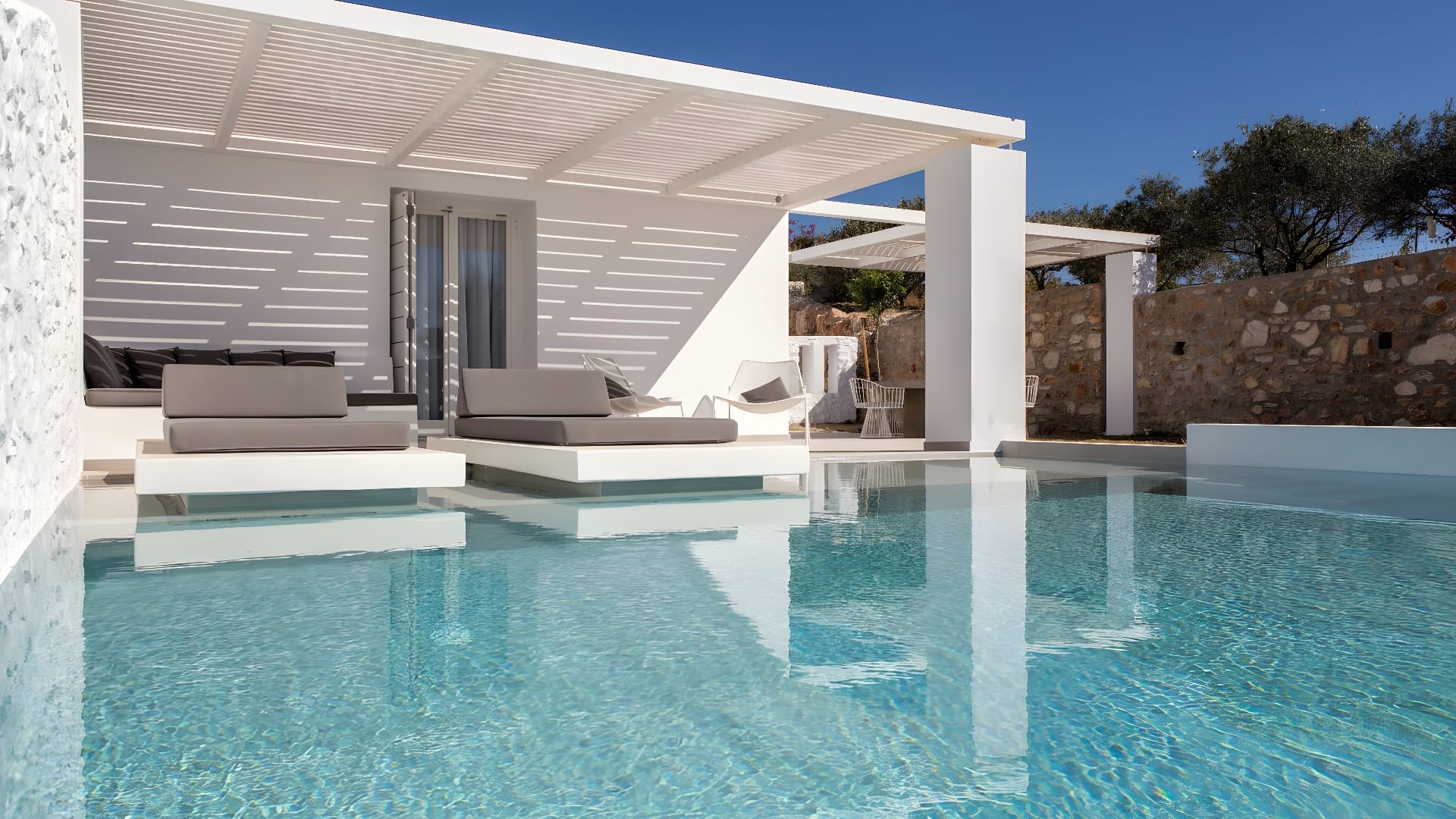 a pool with lounge chairs and a white building