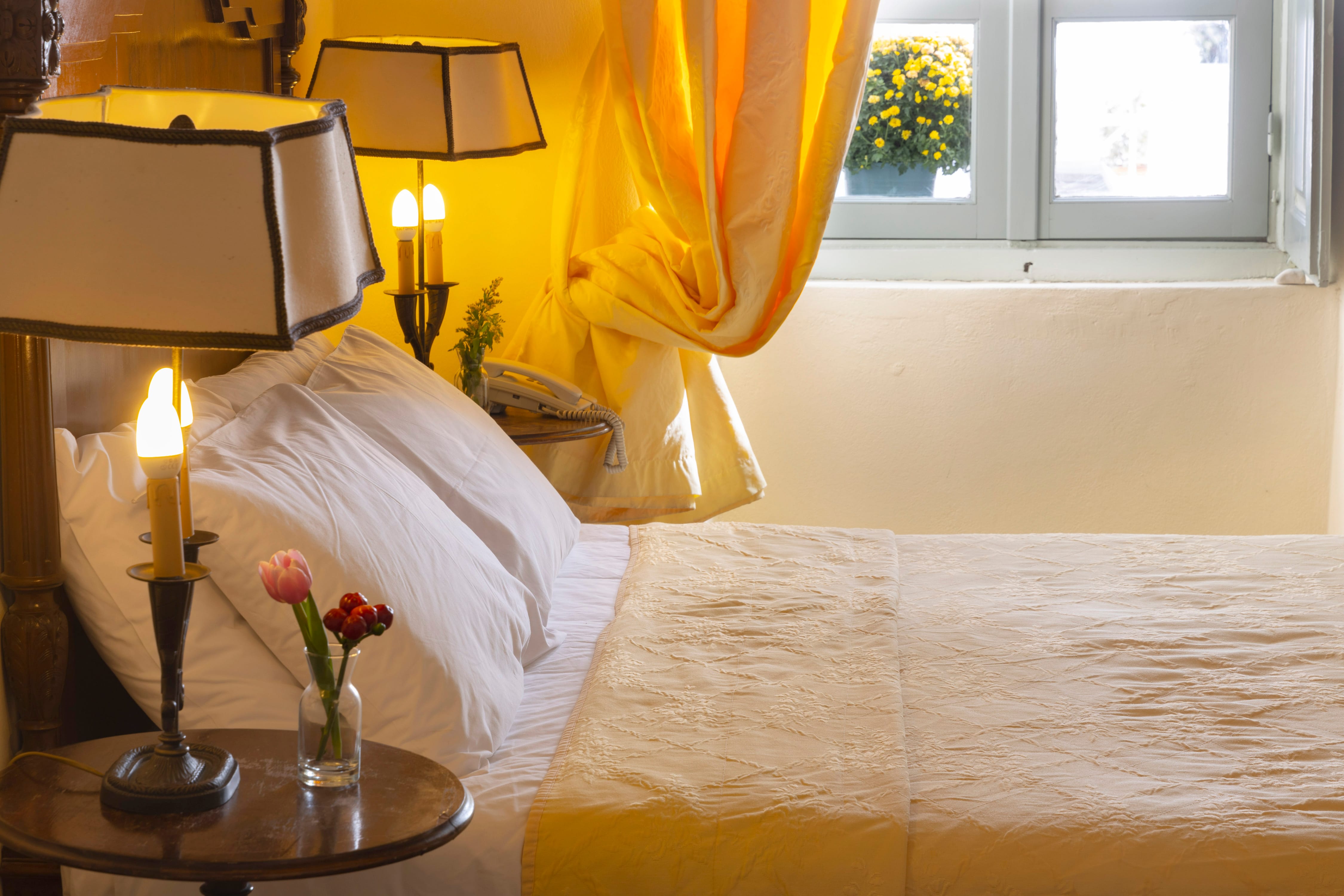 a bed with a lamp and a flower on it