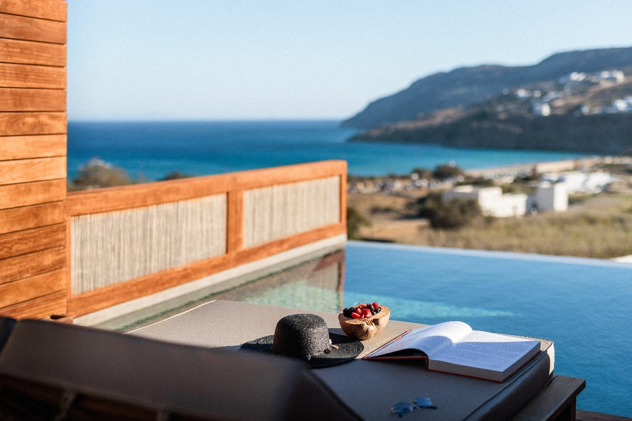 a deck with a table and a plate of food on it by a body of water