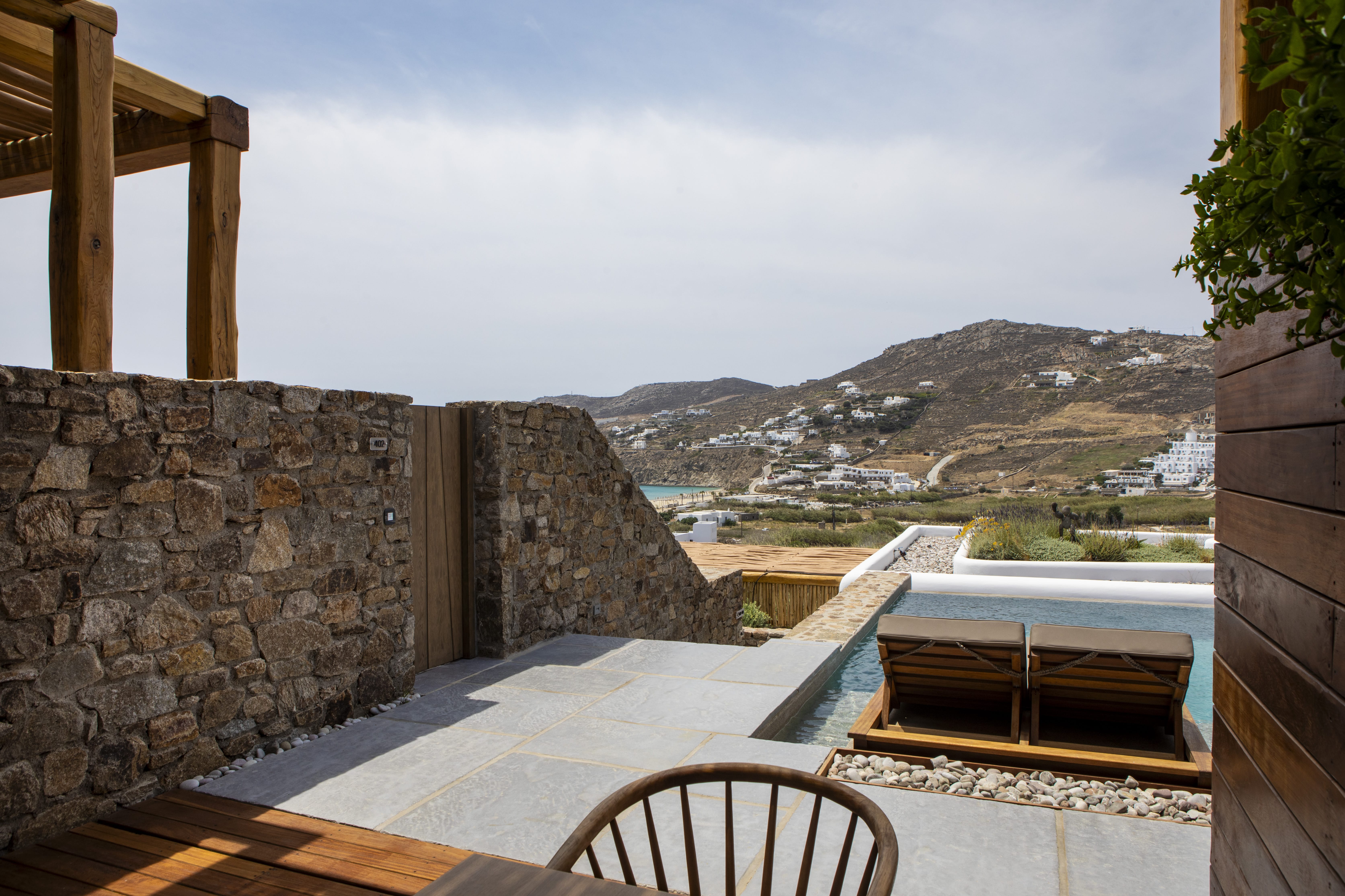 a stone patio with a boat and a stone wall with a view of a town and mountains
